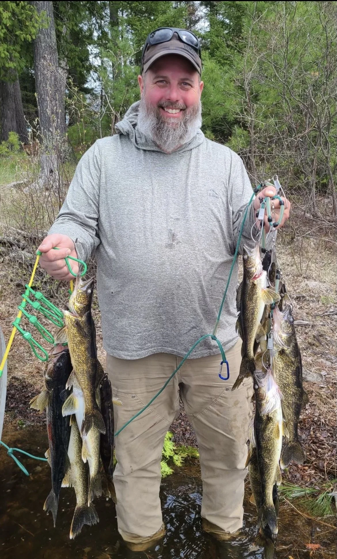 Angler holds walleye stringer in shallows on opener Ely MN, BWCA area, May 14 2024. Arrowhead Outdoors Ely MN fishing report with premium tackle, hunting gear & camping supplies available.