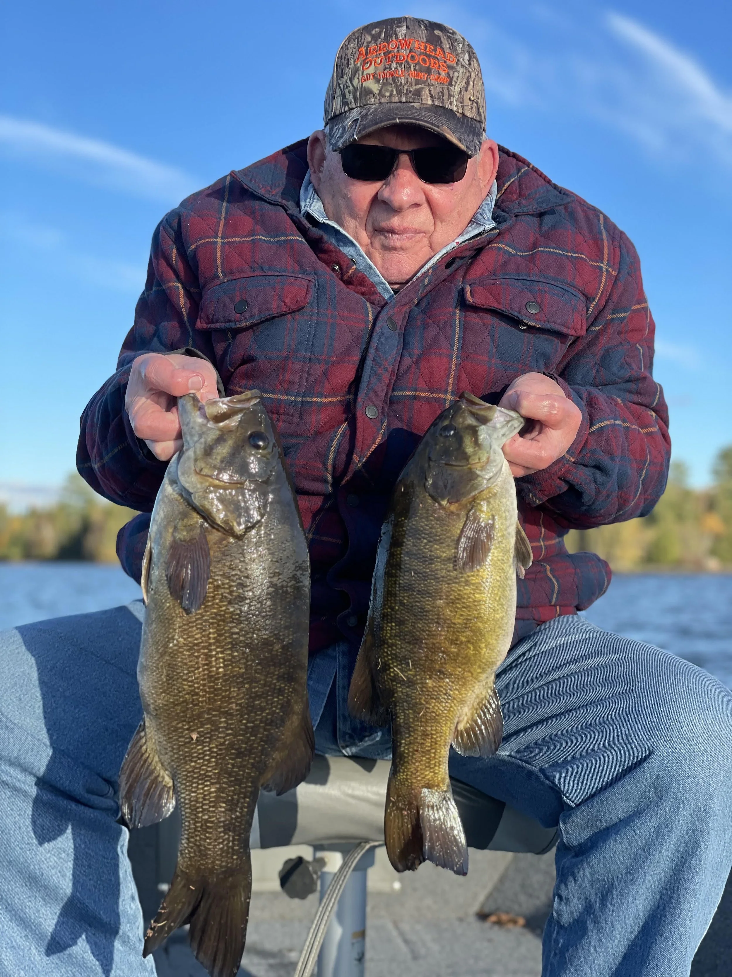 Man holding two giant smallmouth bass caught on Ely area lake near BWCA. Arrowhead Outdoors fishing report.