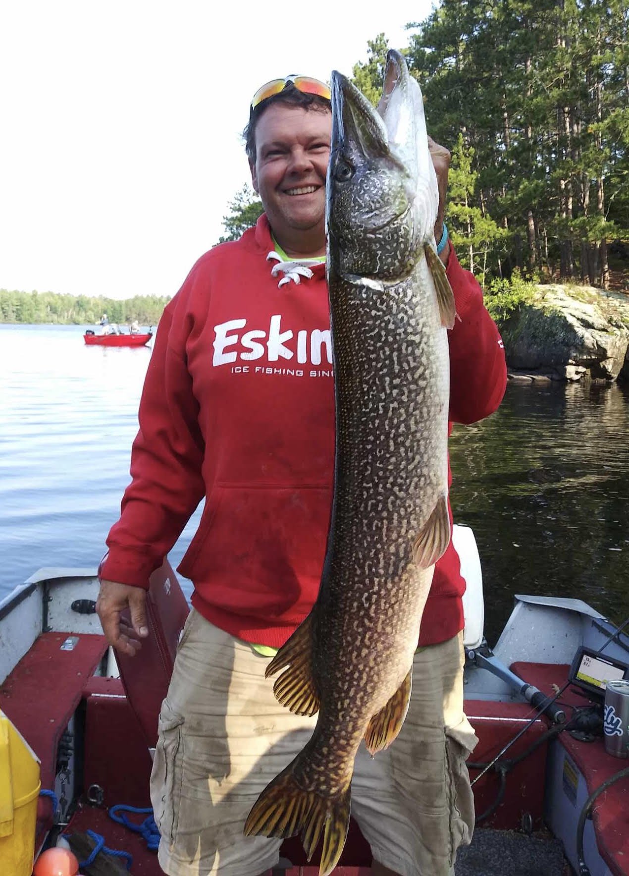 Angler proudly holds large northern pike catch in boat on Ely MN lake, BWCA area, August 29 2023. Arrowhead Outdoors Ely MN fishing report with premium tackle, hunting gear & camping supplies available.