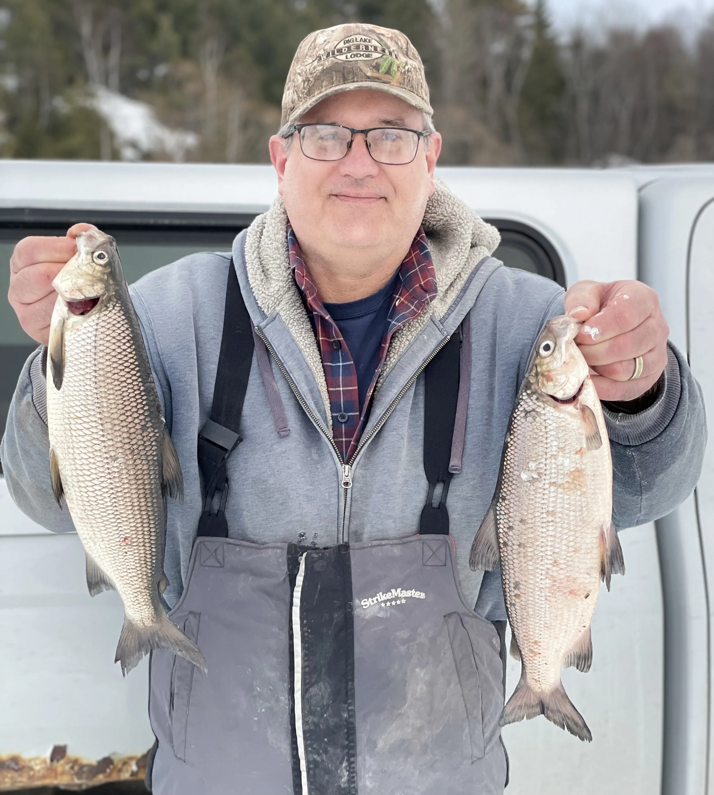Ely MN ice fishing whitefish catch February 2026 BWCA area angler holding two silvery scaled whitefish Arrowhead Outdoors report stream trout lake trout action