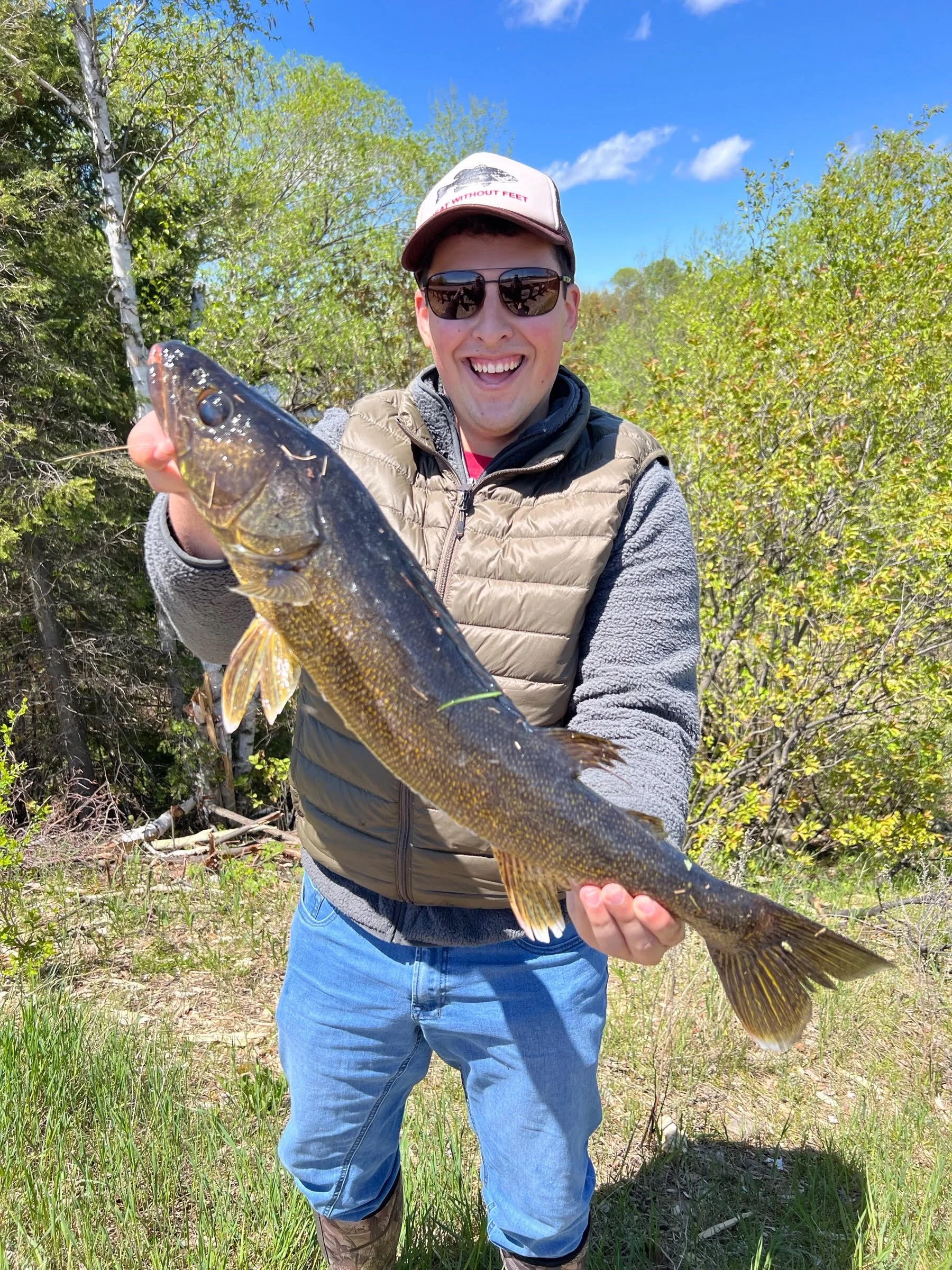 Angler holds walleye caught on rainbow lure on rocky shore Ely MN, BWCA area, May 28 2024. Arrowhead Outdoors Ely MN fishing report with premium tackle, hunting gear & camping supplies available.