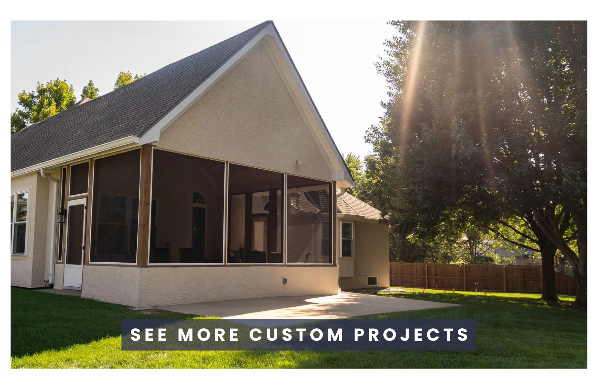 A backyard with a two-story beige house, screened porch, green lawn, trees, and a wooden fence, with sunlight streaming through the trees.