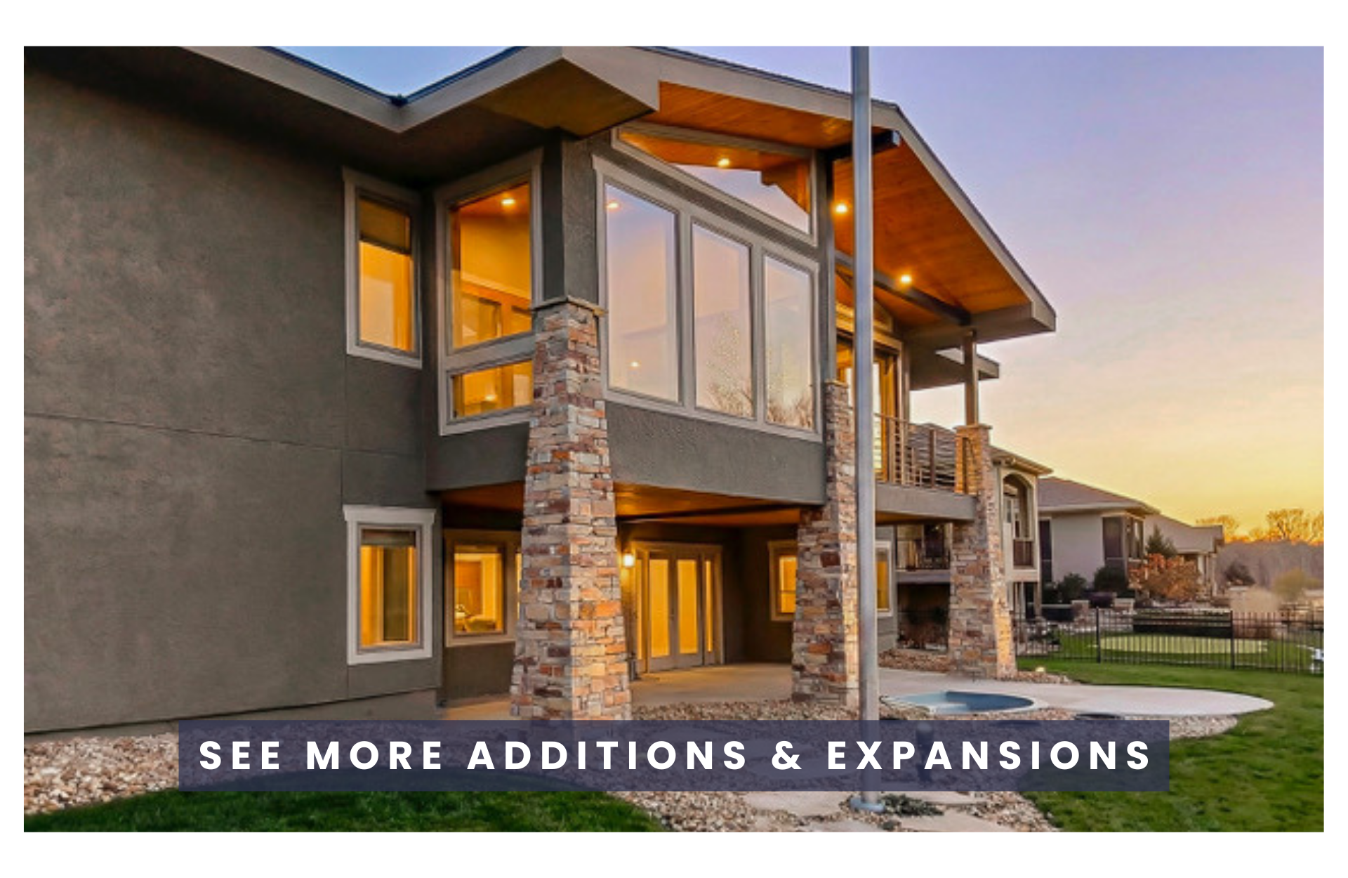 Modern multi-story house with large windows, stone accents, and a patio area at sunset.