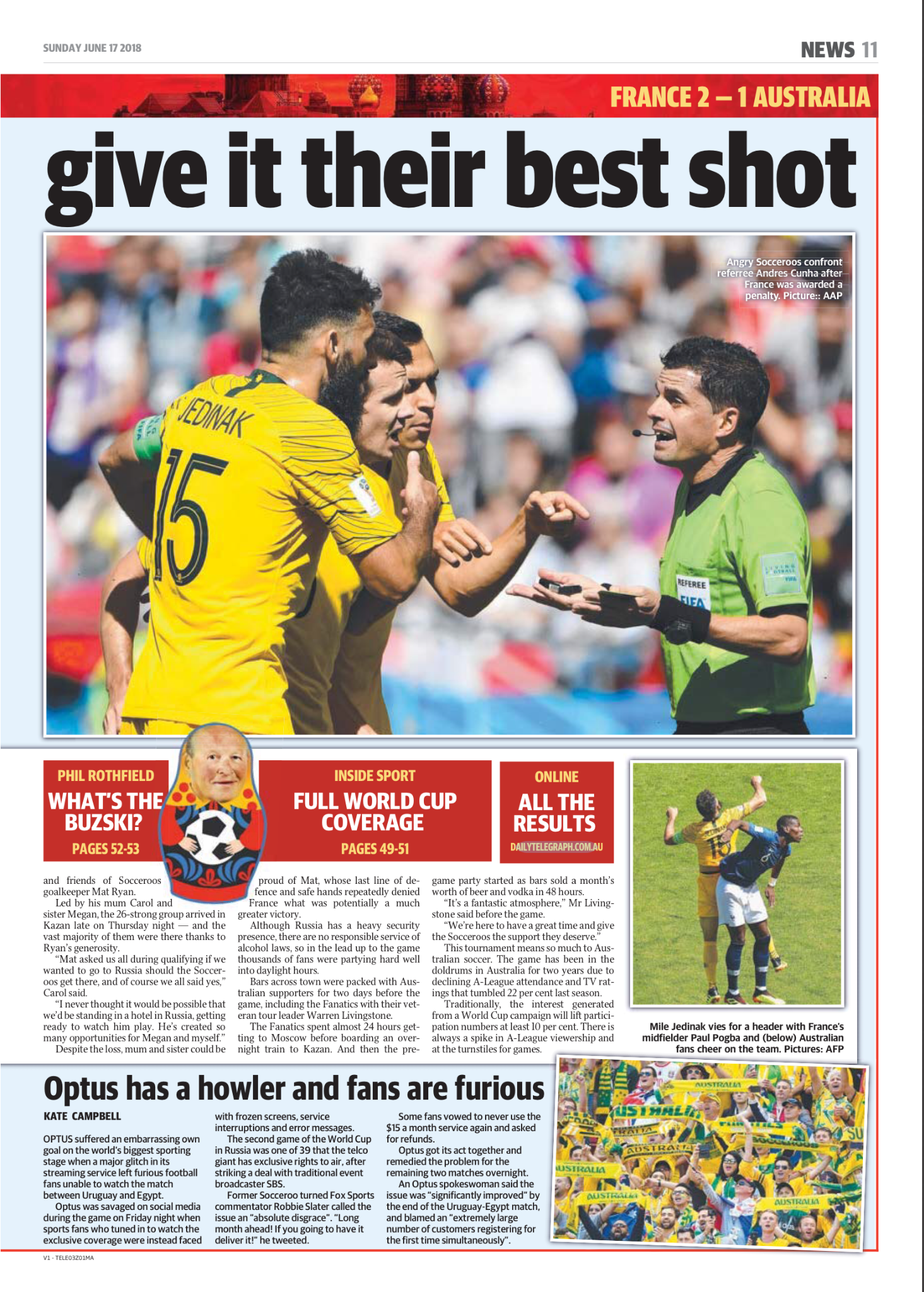 Soccer referees confront a angry player during a match, with spectators blurred in the background.