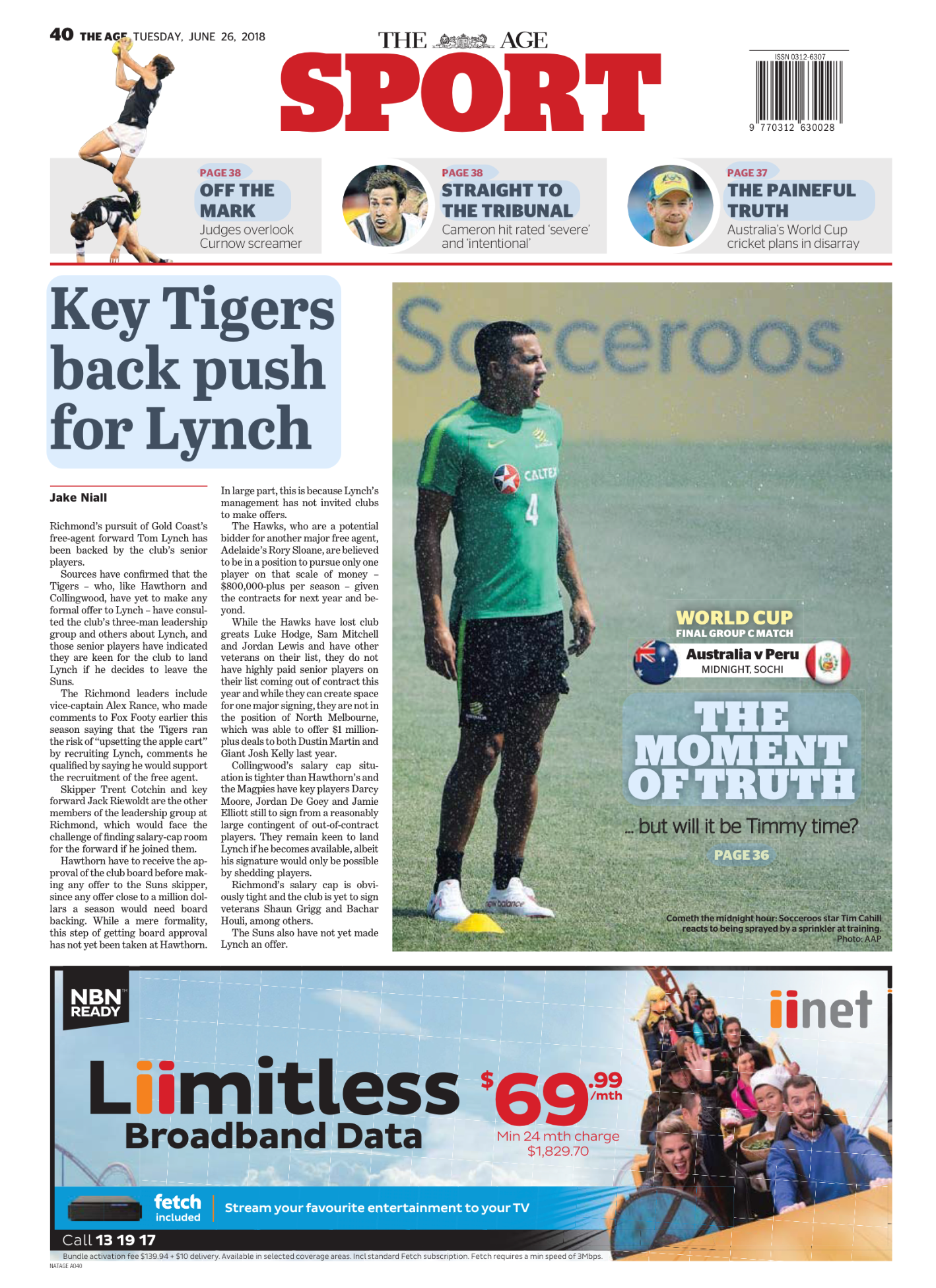 Newspaper page from The Age Sports section featuring an article about the push for Lynch by key Tigers players, and a photo of a soccer player in green training gear during the World Cup match Australia versus Peru, reacting to being sprayed by a spr