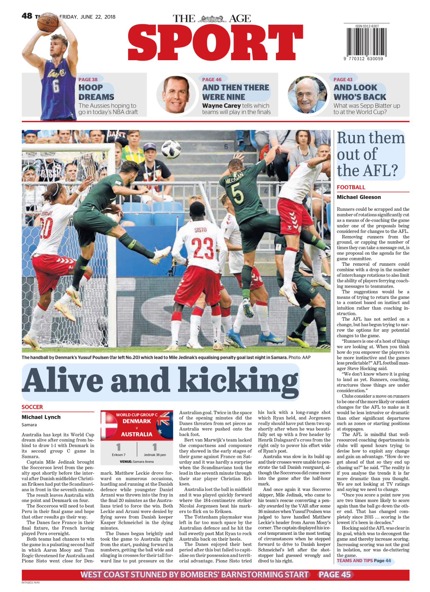 A soccer match between Denmark and Australia taking place in a stadium. Danish players in green jerseys are jumping to head the ball, while Australian players in white and red jerseys are positioned on the ground and nearby. Spectators can be seen in