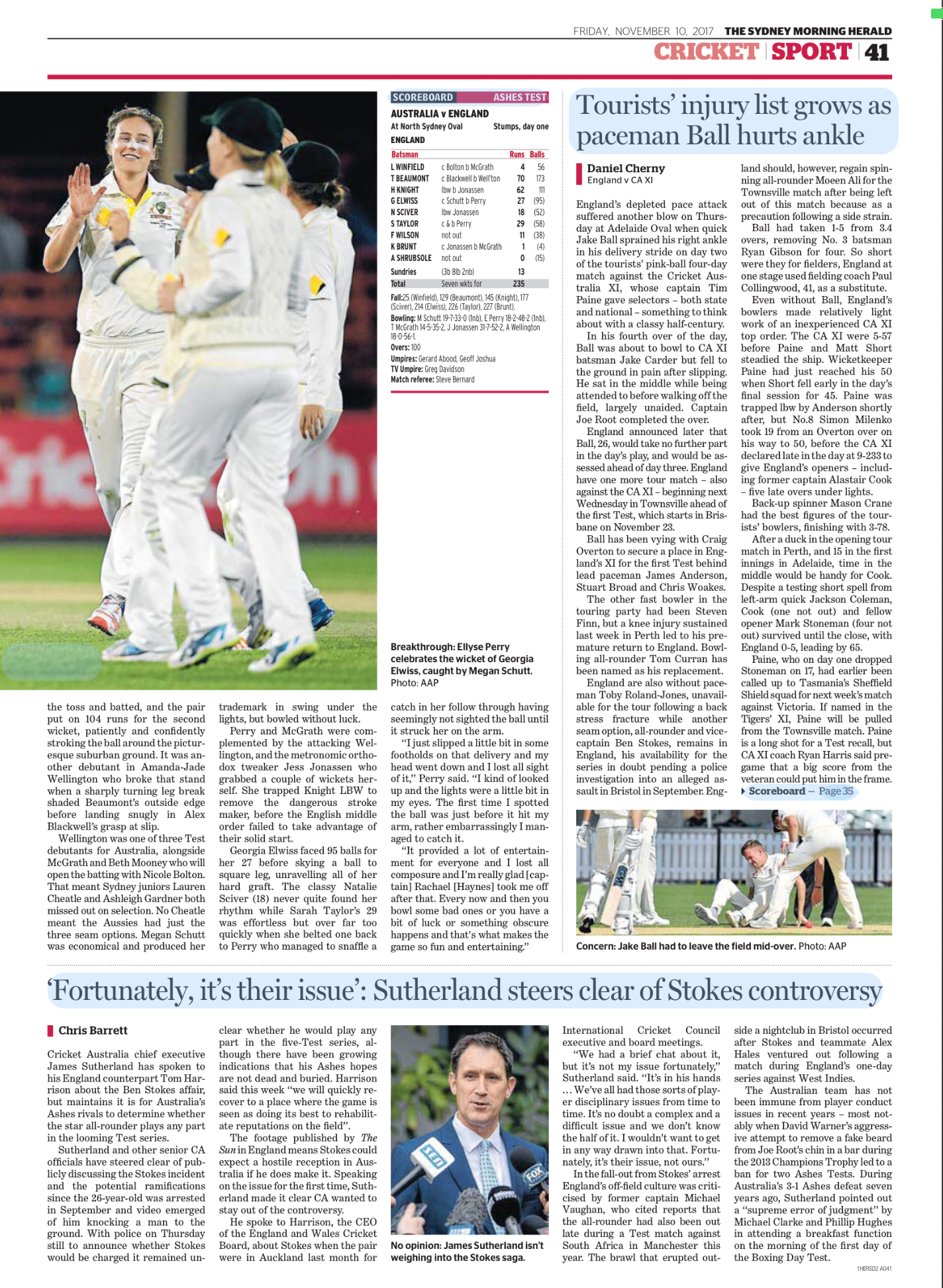 Cricket players celebrating on the field with a smiling female player in focus. Other players in the background, wearing white uniforms, are seen from behind.