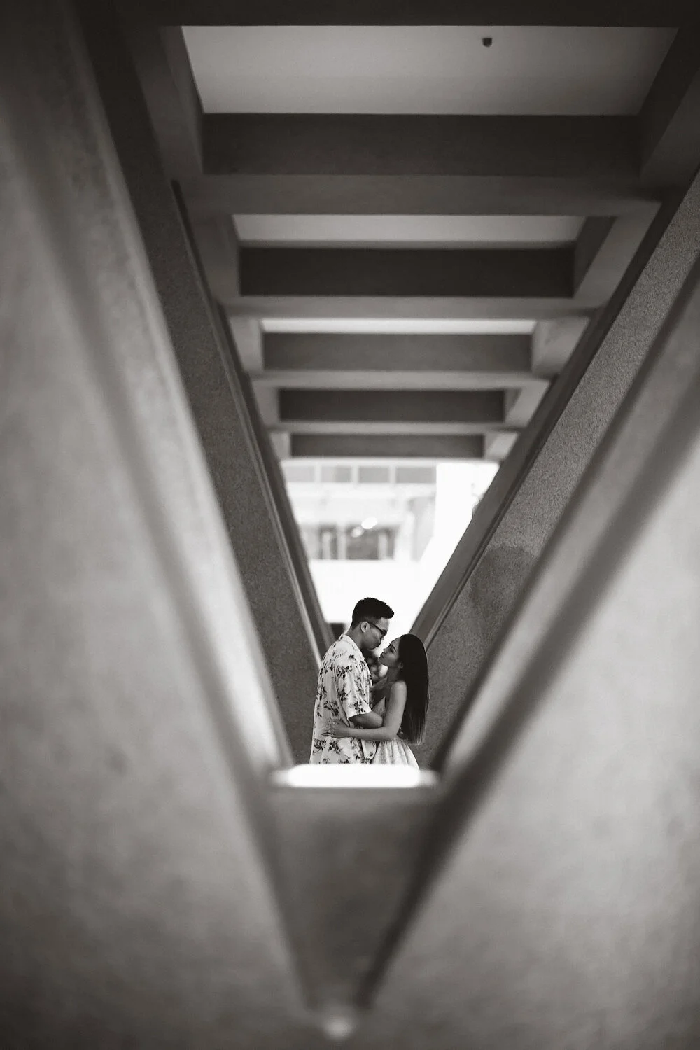 Couple embracing in a modern architectural hallway, black and white photo.
