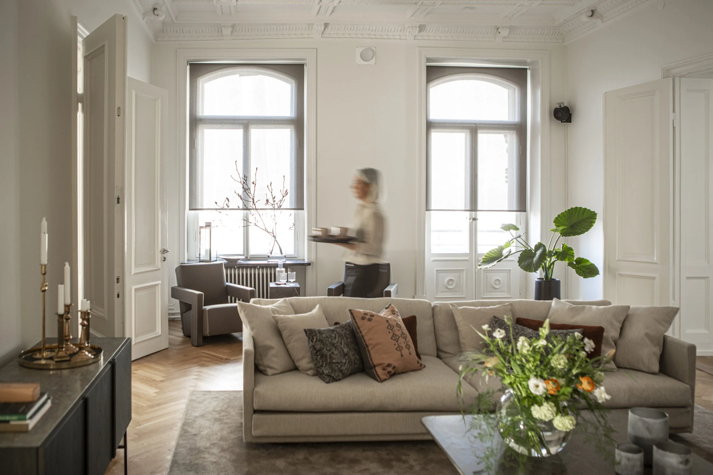 Valoisa ja maalaisromanttinen olohuone, jossa kaksi ikkunaa vaalealla screen-rullakaihtimella.