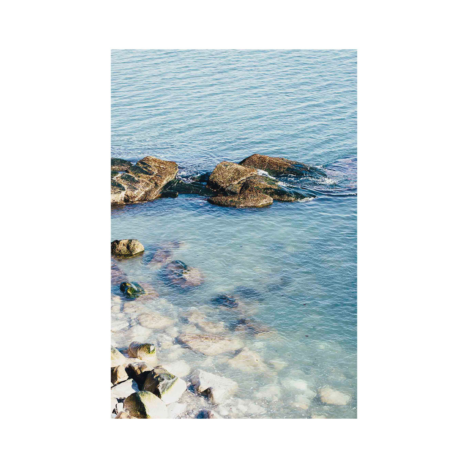 Unframed mounted vertical fine art photography of calm low tide turquoise waters on a white rocky shore.