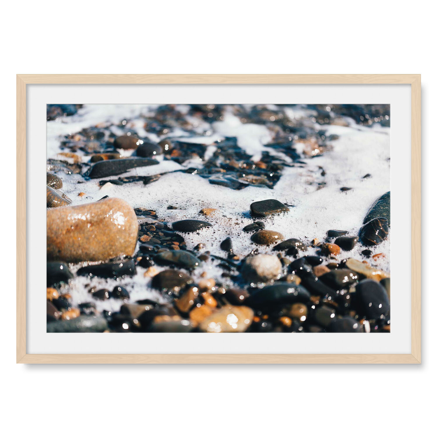 Light maple solid hardwood framed horizontal fine art photography closeup of beach stones freshly washed by a retreating wave.