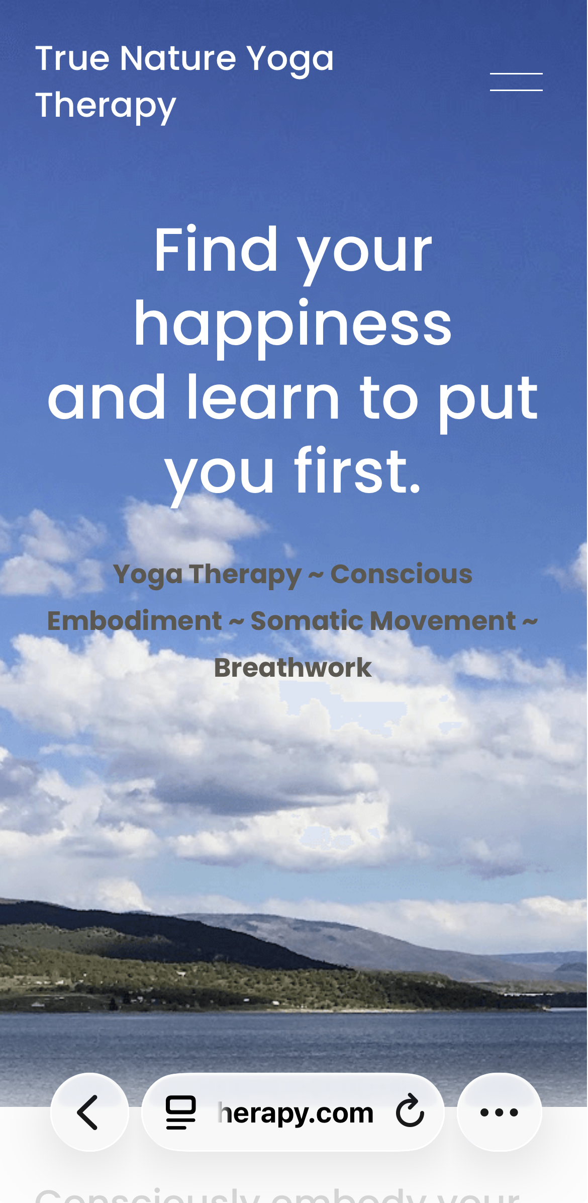 A scenic view of a lake with hills and a partly cloudy sky in the background, with overlaid text promoting True Nature Yoga Therapy and related practices.