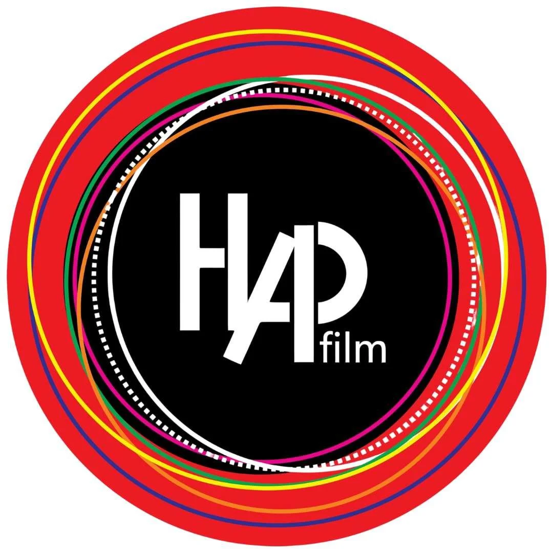 Logo with the text 'HAP film' in a black circle surrounded by colorful concentric circles on a red background.