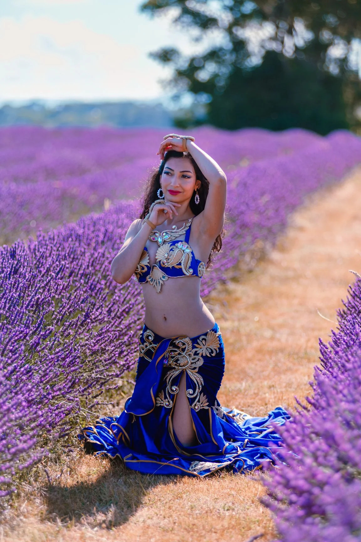 Woman in ornate blue costume posing in a lavender field.