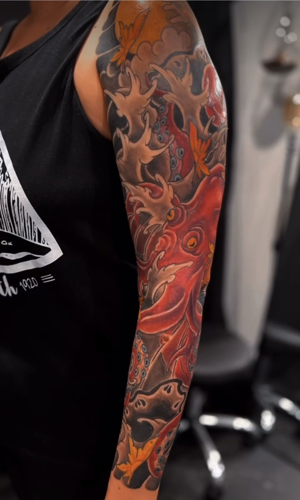 Colorful full sleeve tattoo featuring a dragon and abstract patterns.