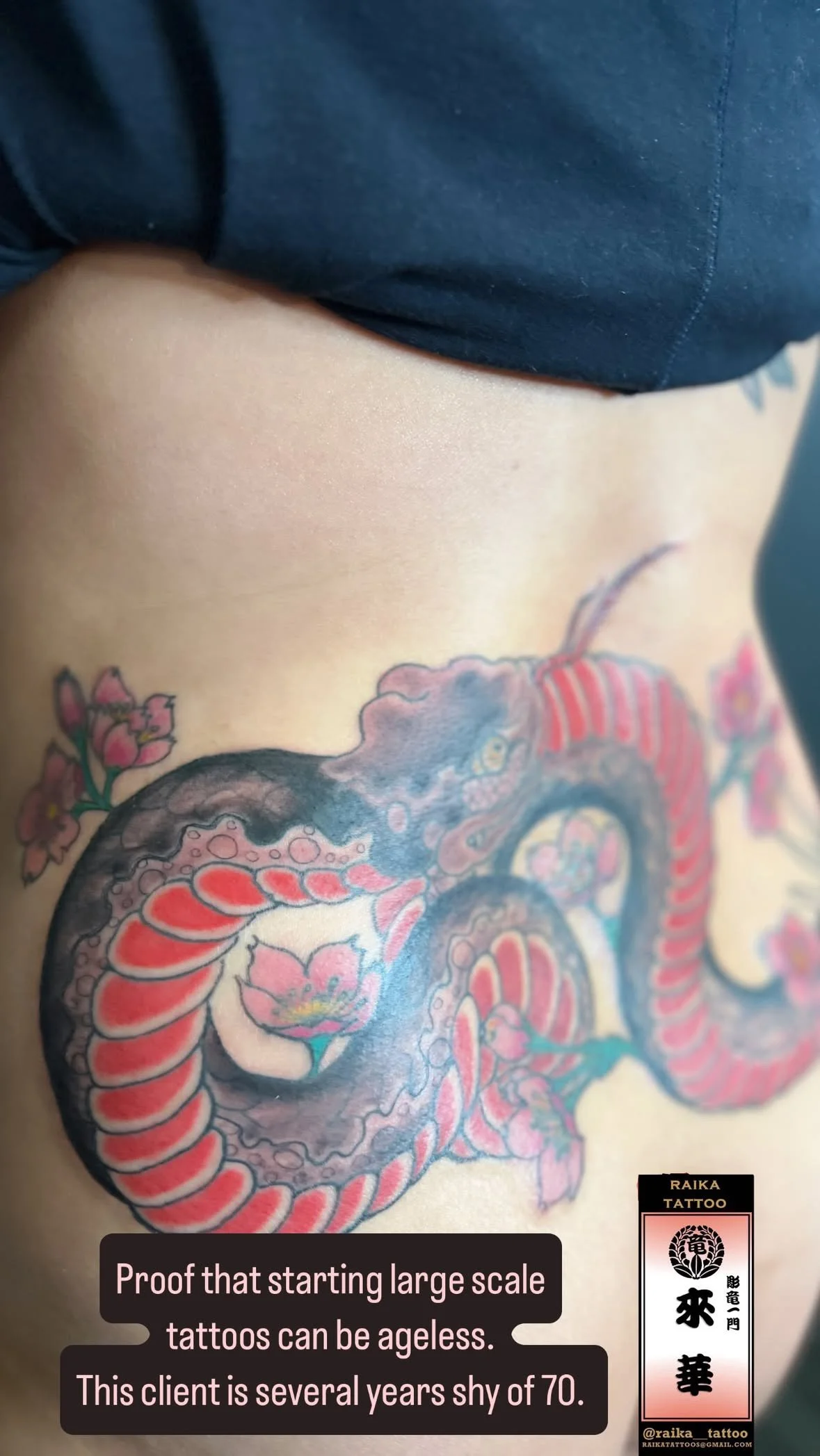 Close-up of a person's side torso featuring a colorful, traditional-style dragon tattoo along with pink cherry blossoms. The photo includes a caption: 'Proof that starting large scale tattoos can be ageless. This client is several years shy of 70.' a