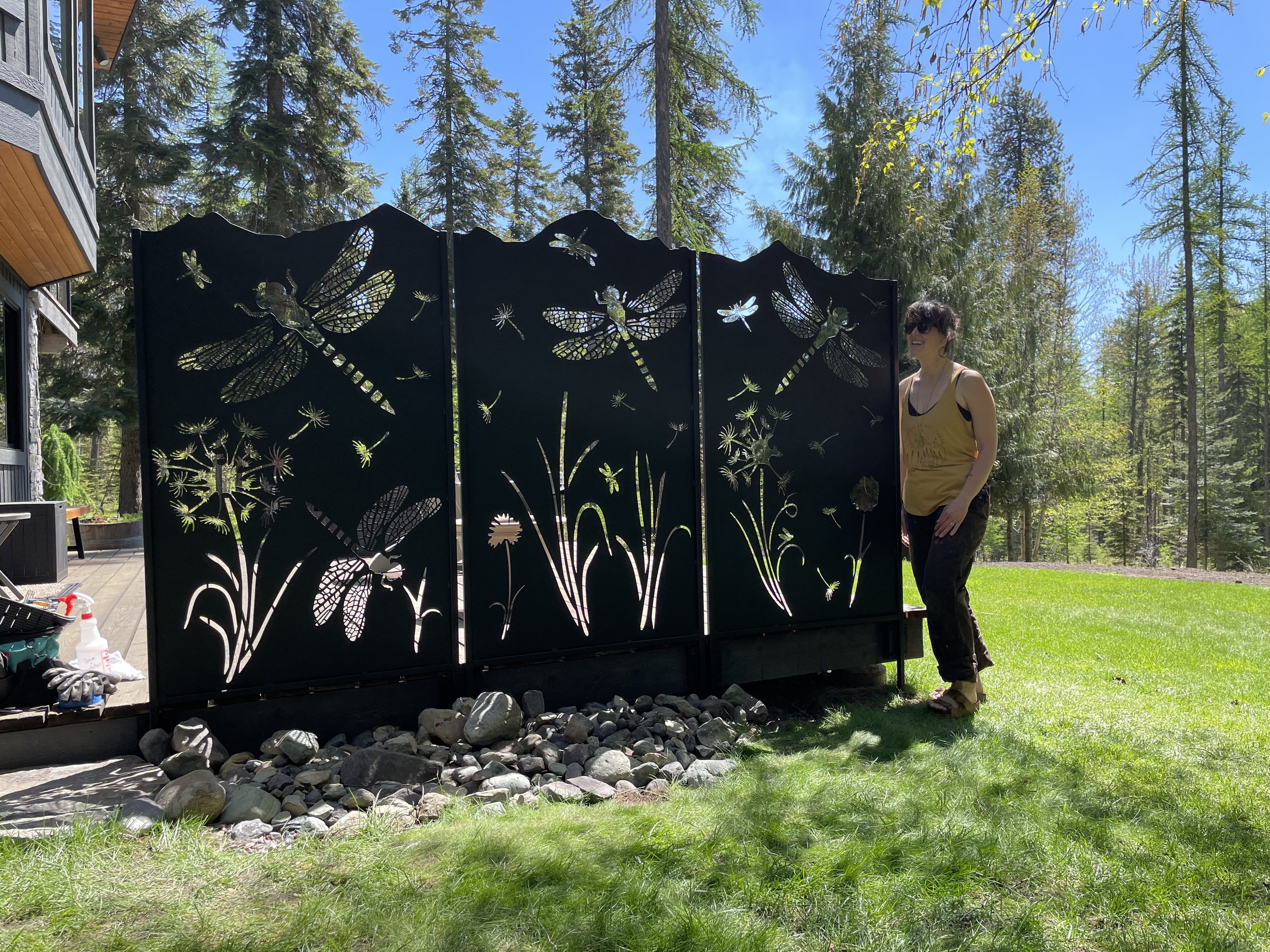 Custom steel dragonfly and dandelion privacy screen set install on a deck to block the view of the road from a hot tub.