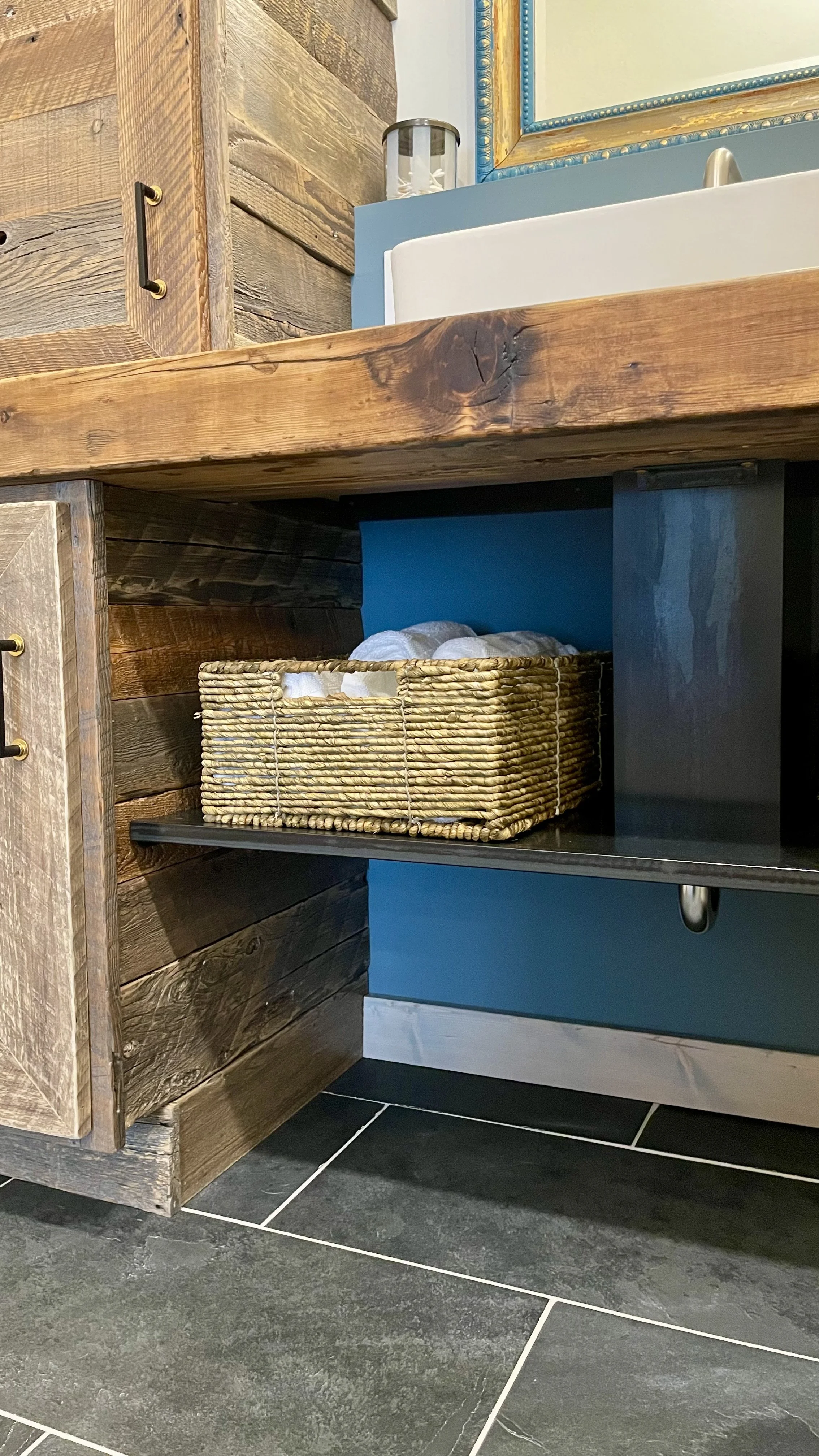 Close up of custom hand made reclaimed wood and steel bathroom vanity with steel open concept shelf and plumbing cover.  Reclaimed wood beam counter finished with epoxy resin, designed and hand crafted by Creative Combinations Montana.