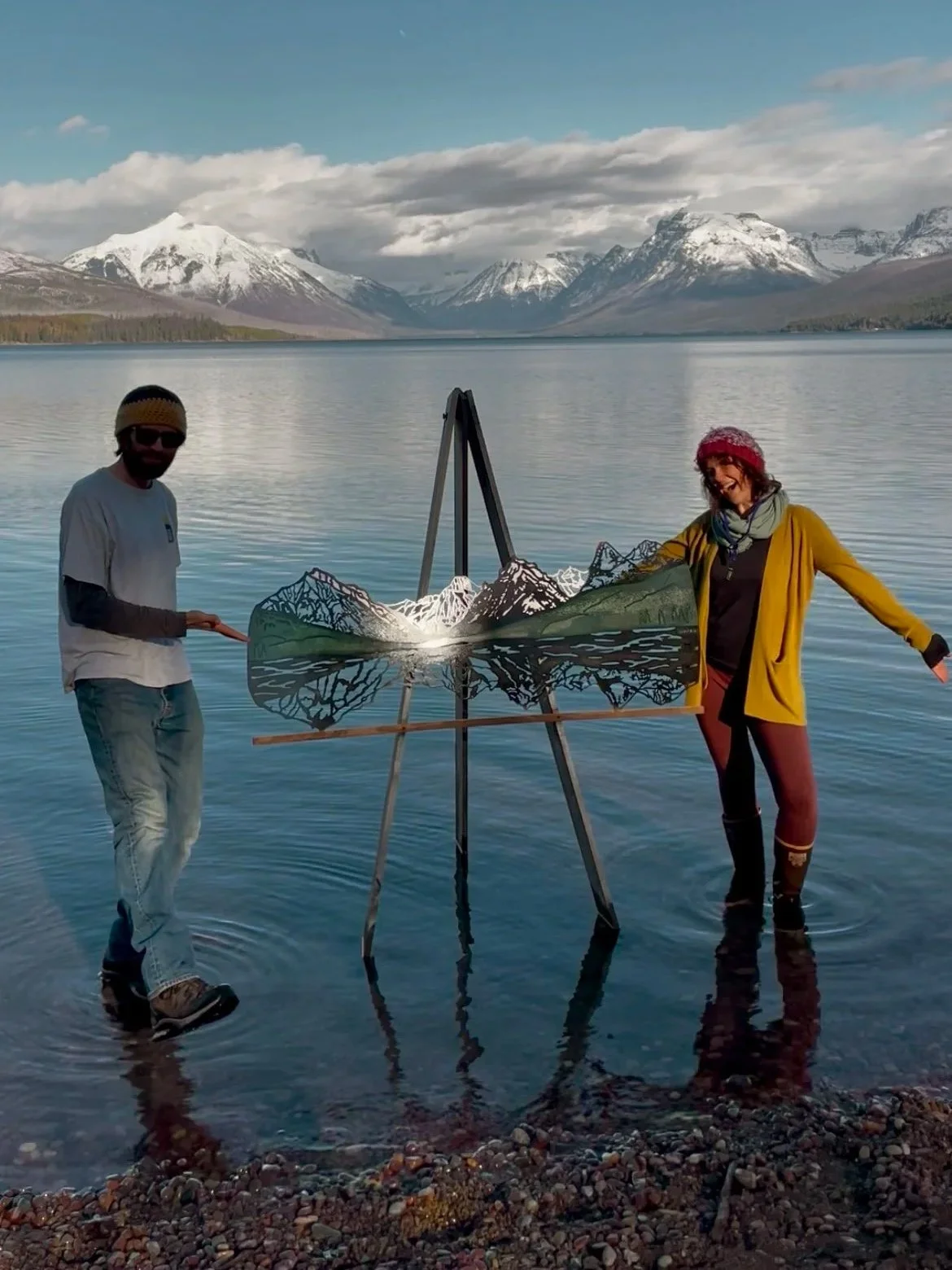 Creative Combinations Montana owners Nate and Kelsey with their new triple layer Lake McDonald mountain metal wall art piece on the shore of Lake McDonald in Glacier National Park.