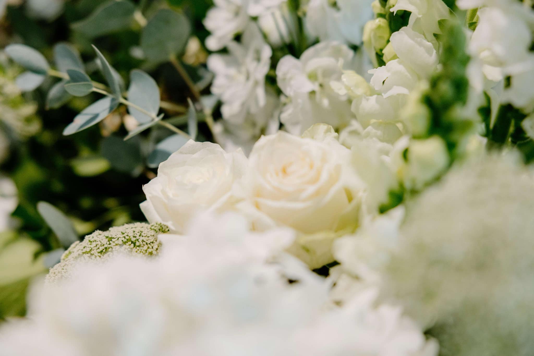 Close-up of white roses and greenery in a floral arrangement.