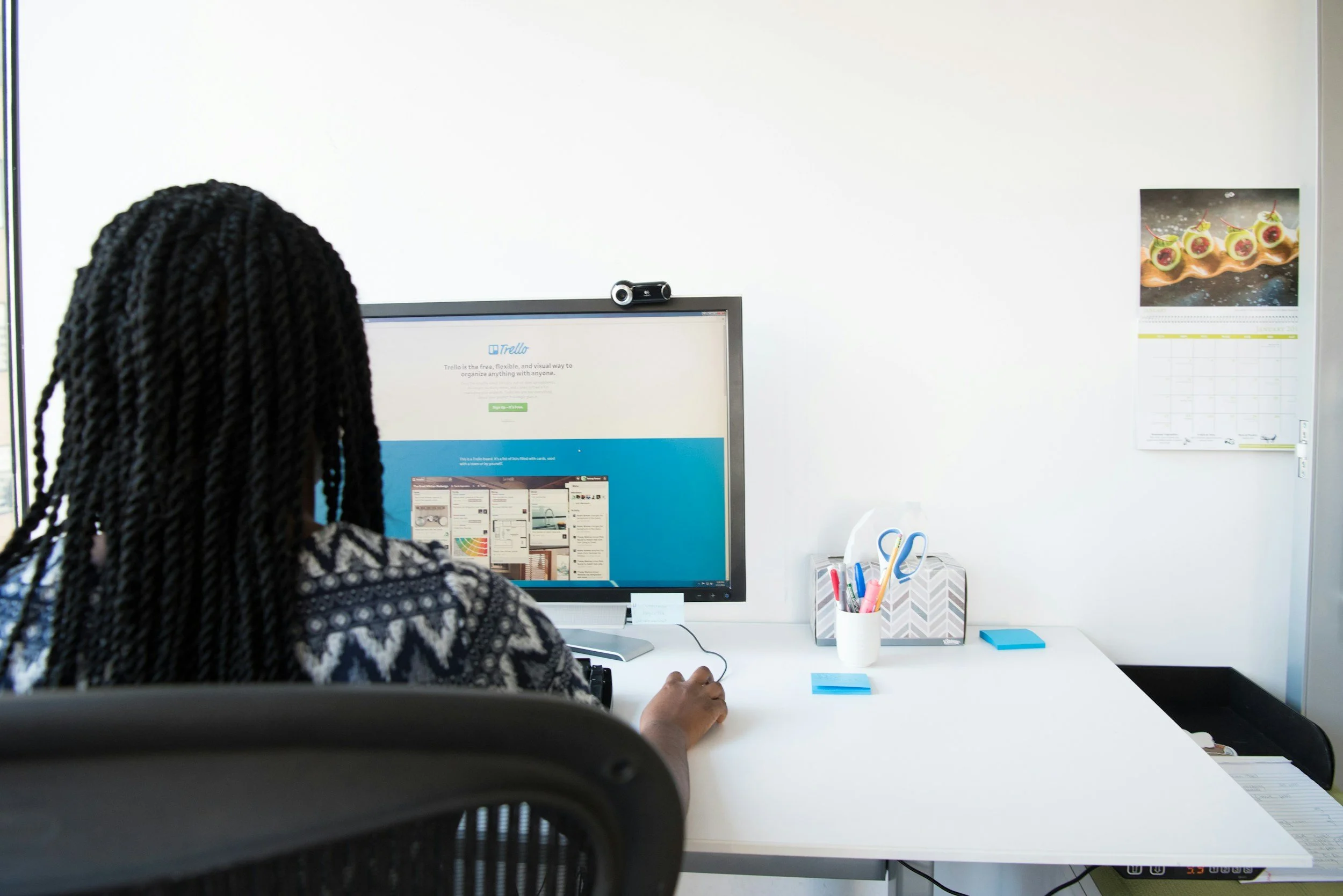 A woman a desk and screen, working on project management.