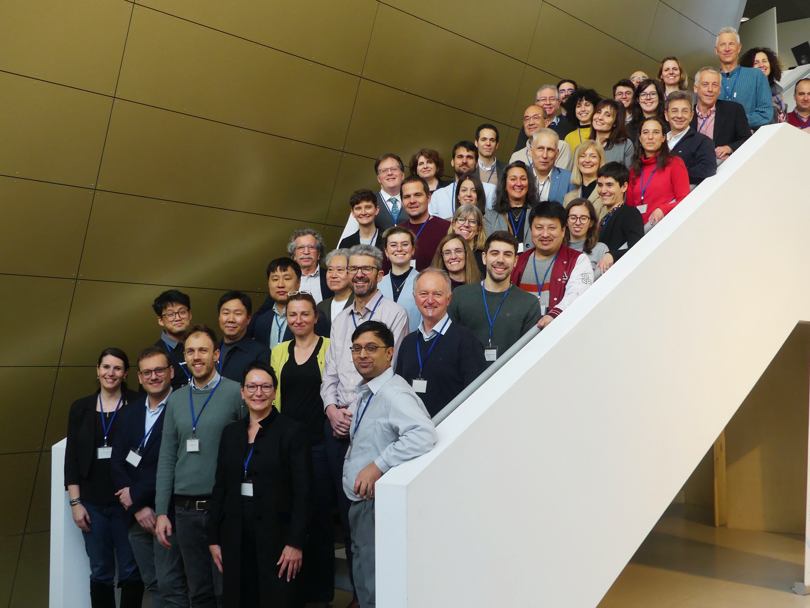 Research project team of over thirty people, posing for a group photo on white stairs.