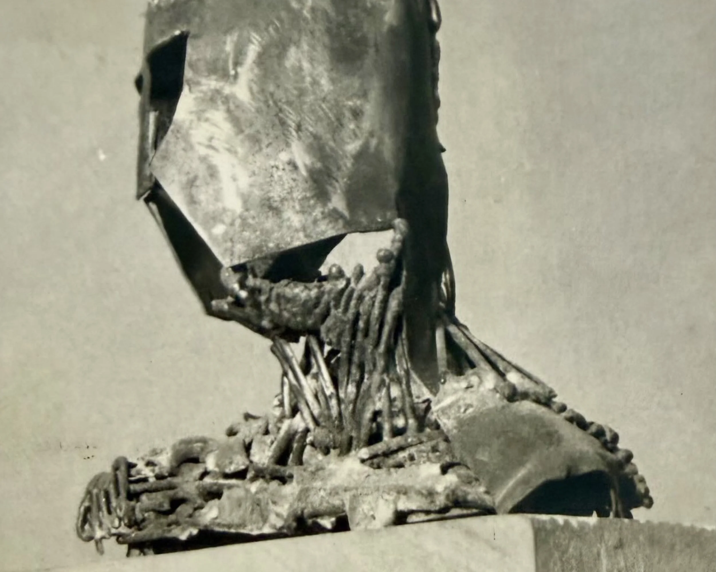 Side view of a welded steel sculpture depicting a head wearing a Norman helmet