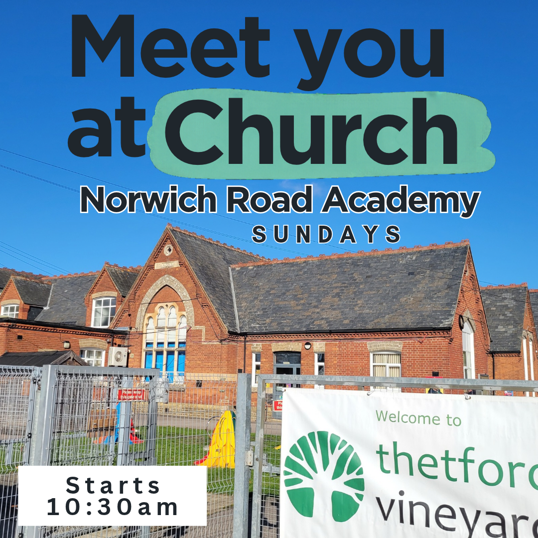 Sign advertising church meetings at Norwich Road Academy, with details about Sunday services starting at 10:30 am, and a banner welcoming to Thetford Vineyard, featuring the church's green tree logo, in front of a red brick church building with a gabled roof.
