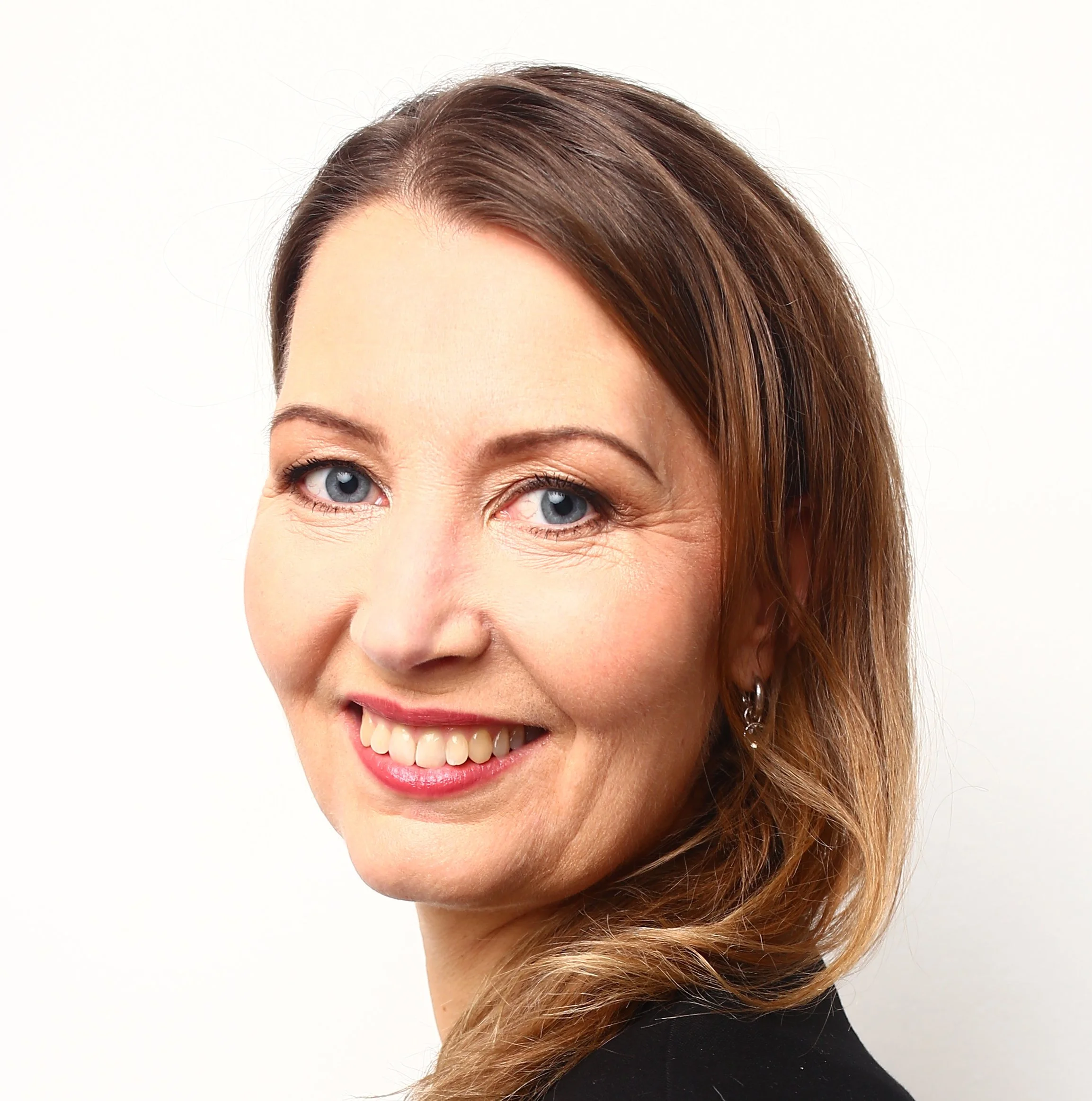 Porträtt av en leende kvinna med brunt hår och blå ögon, iförd svart plagg.