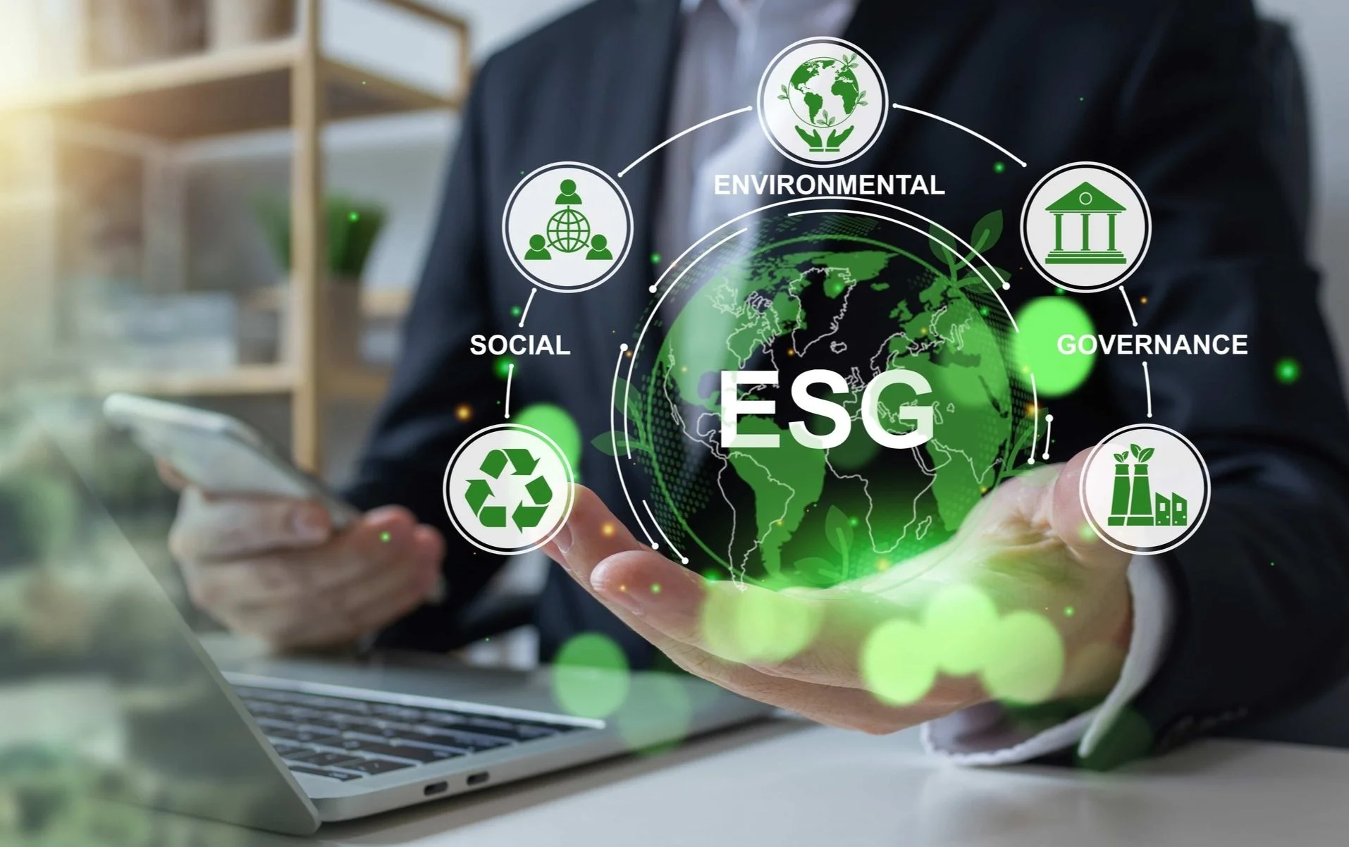 En person håller ut handen med en digital illustration av jorden och begreppet ESG, omgiven av ikoner som representerar miljö, sociala frågor, styrning och hållbarhetsaspekter, framför en laptop.