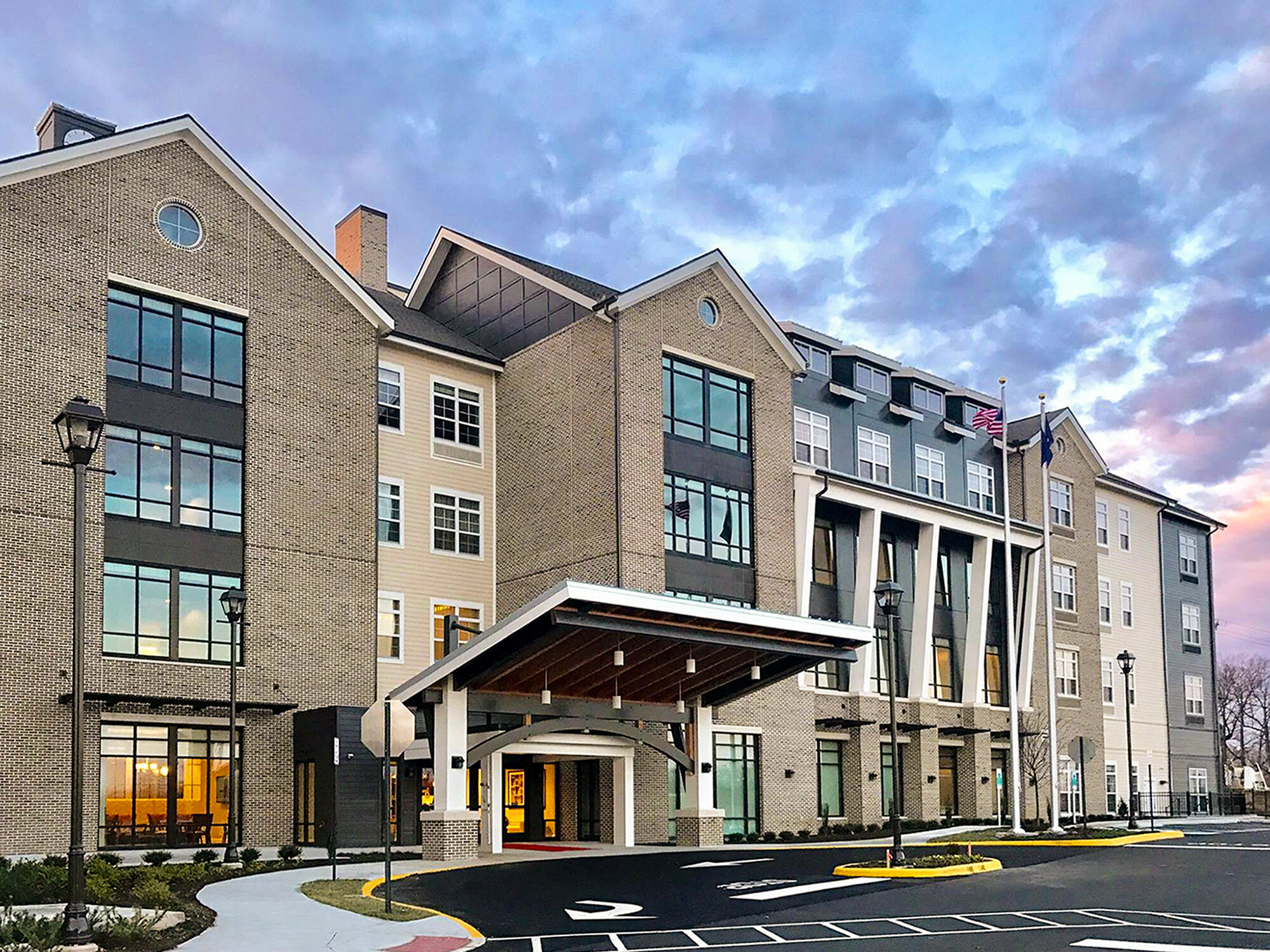 Exterior of Tribute at the Glen building. This image features the covered entrance where guests can temporarily park to enter the building and many glass windows for each room