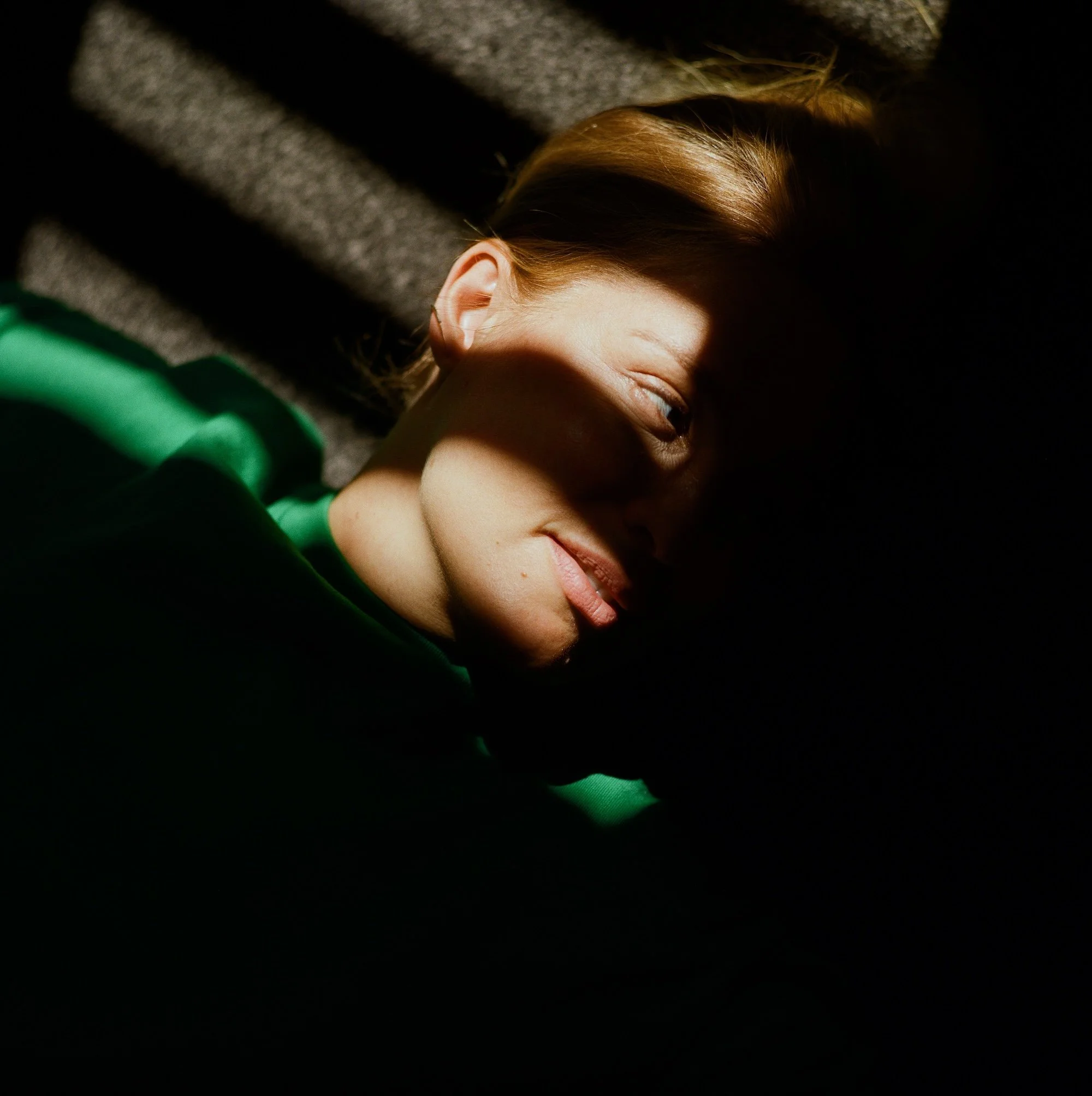 Porträt einer Frau im Halbschatten mit Lichtstreifen auf dem Gesicht.