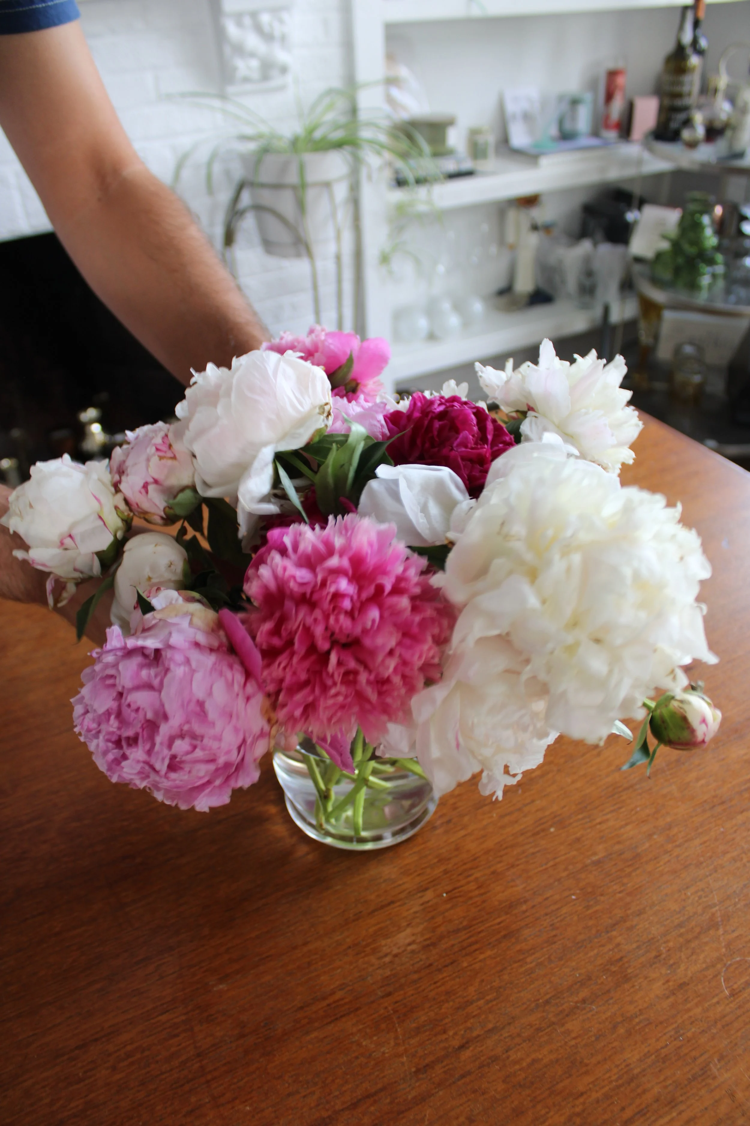 Large peony bouquet centerpiece on a dining room table featuring soft pink and white blooms.