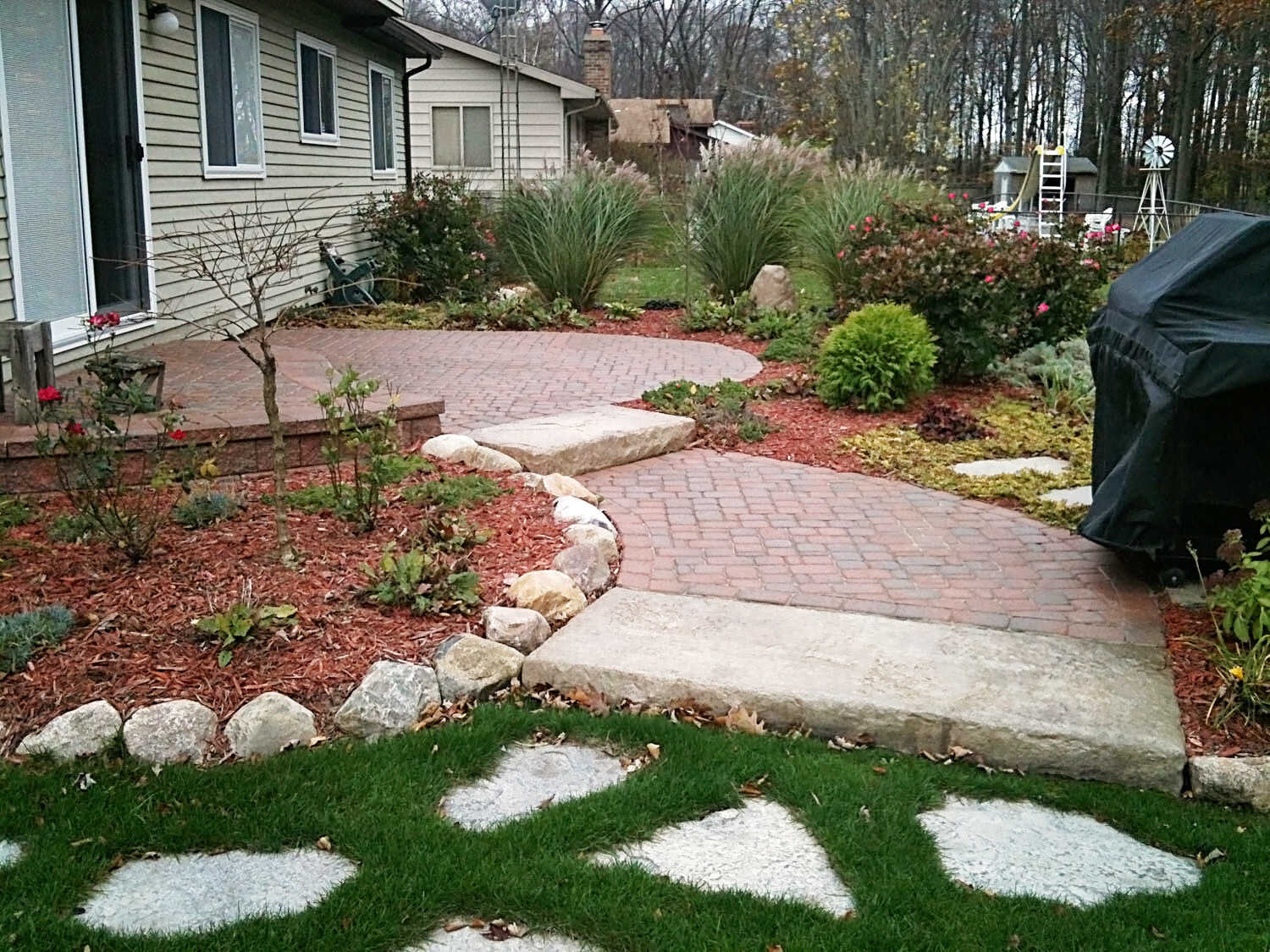  tiered patio with pavers and gardens with shrubs and trees | Flint Michigan landscapers H&amp;M Landscaping 
