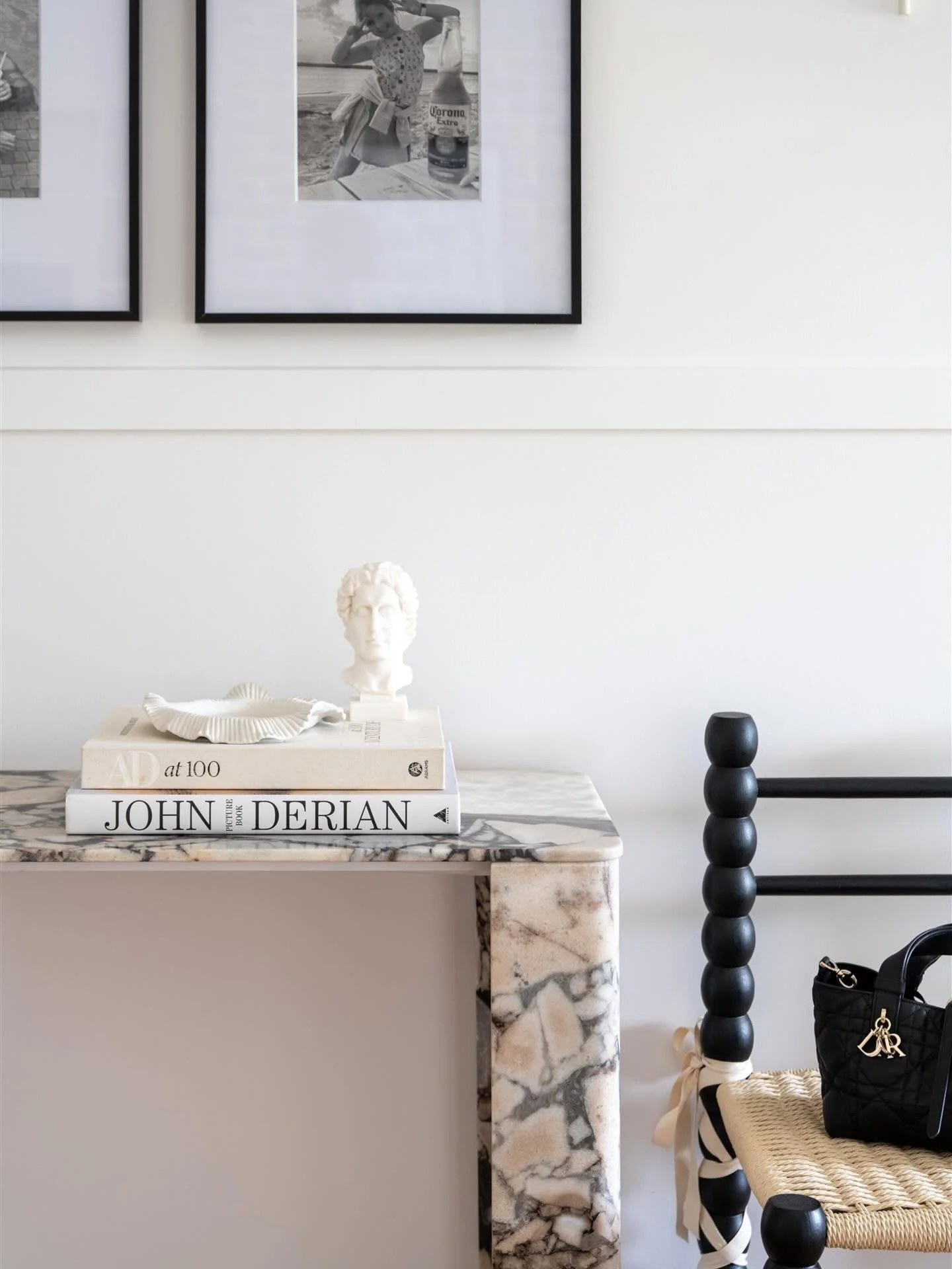 Marble, memories and considered details. 
A small moment from the entryway at Maison de toujours blends family photos, a delicate ruffled tray from local ceramicist @thompsonlane___ and ribbon tied chair - a subtle ballet inspired gesture adding a pe