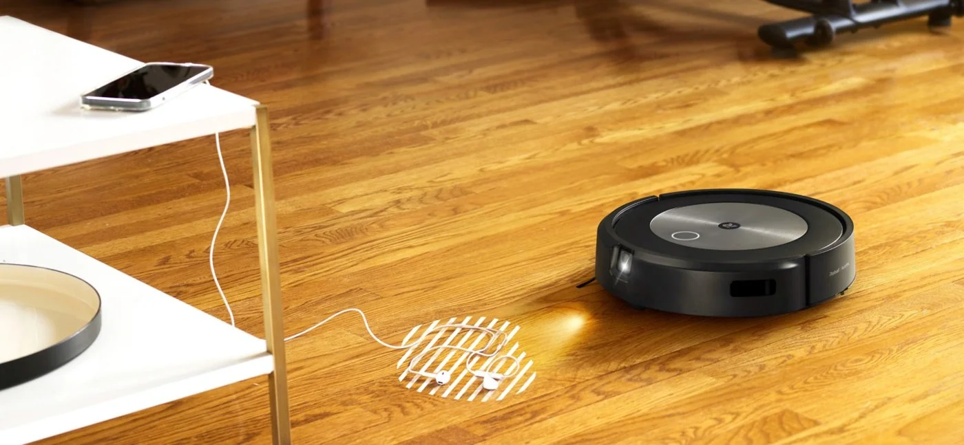 marketing image of the robot avoiding a pair for corded headphones on the floor.