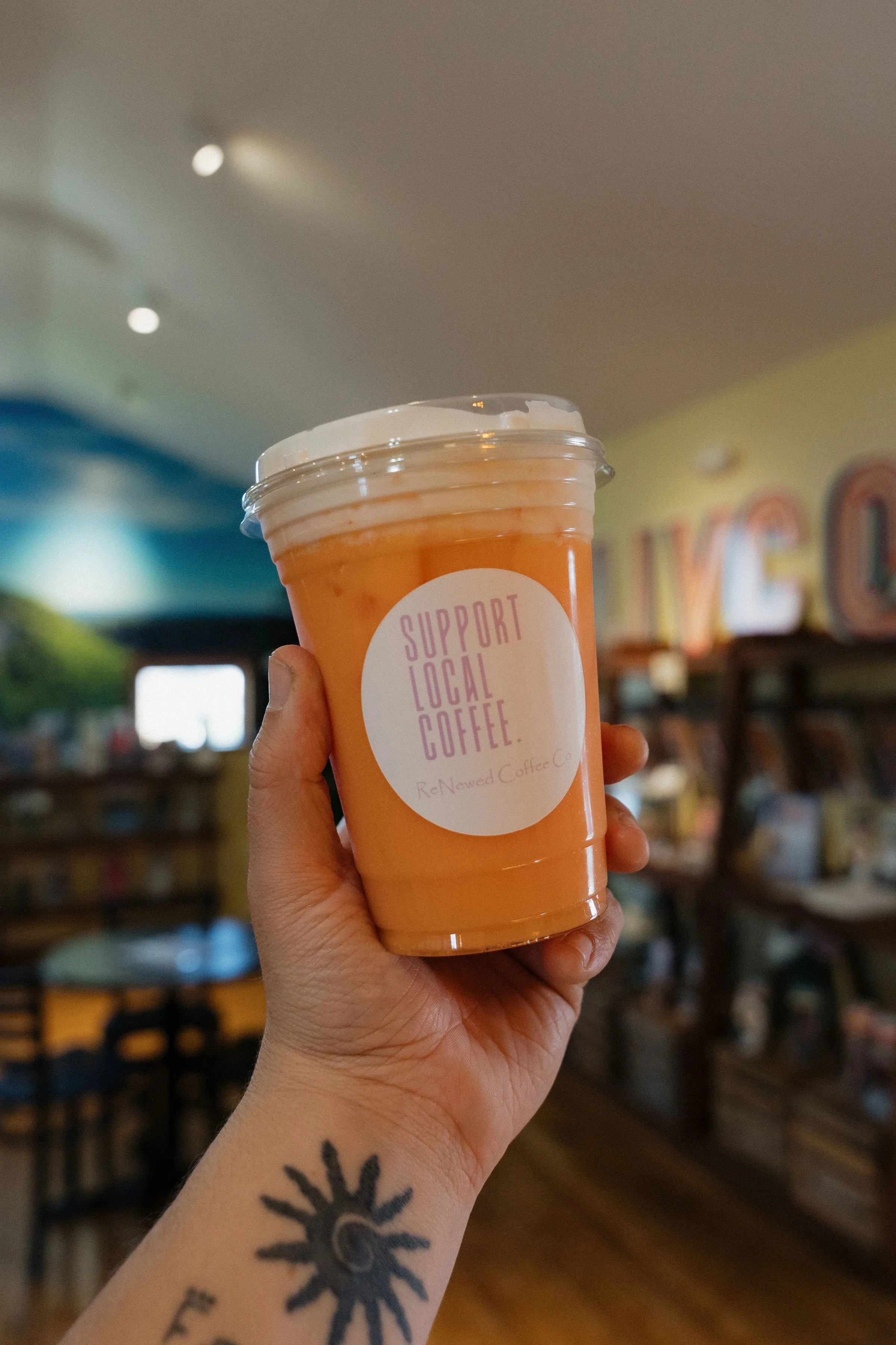 Holding up iced orange coffee drink at ReNewed Coffee Co Mount Morris.jpg