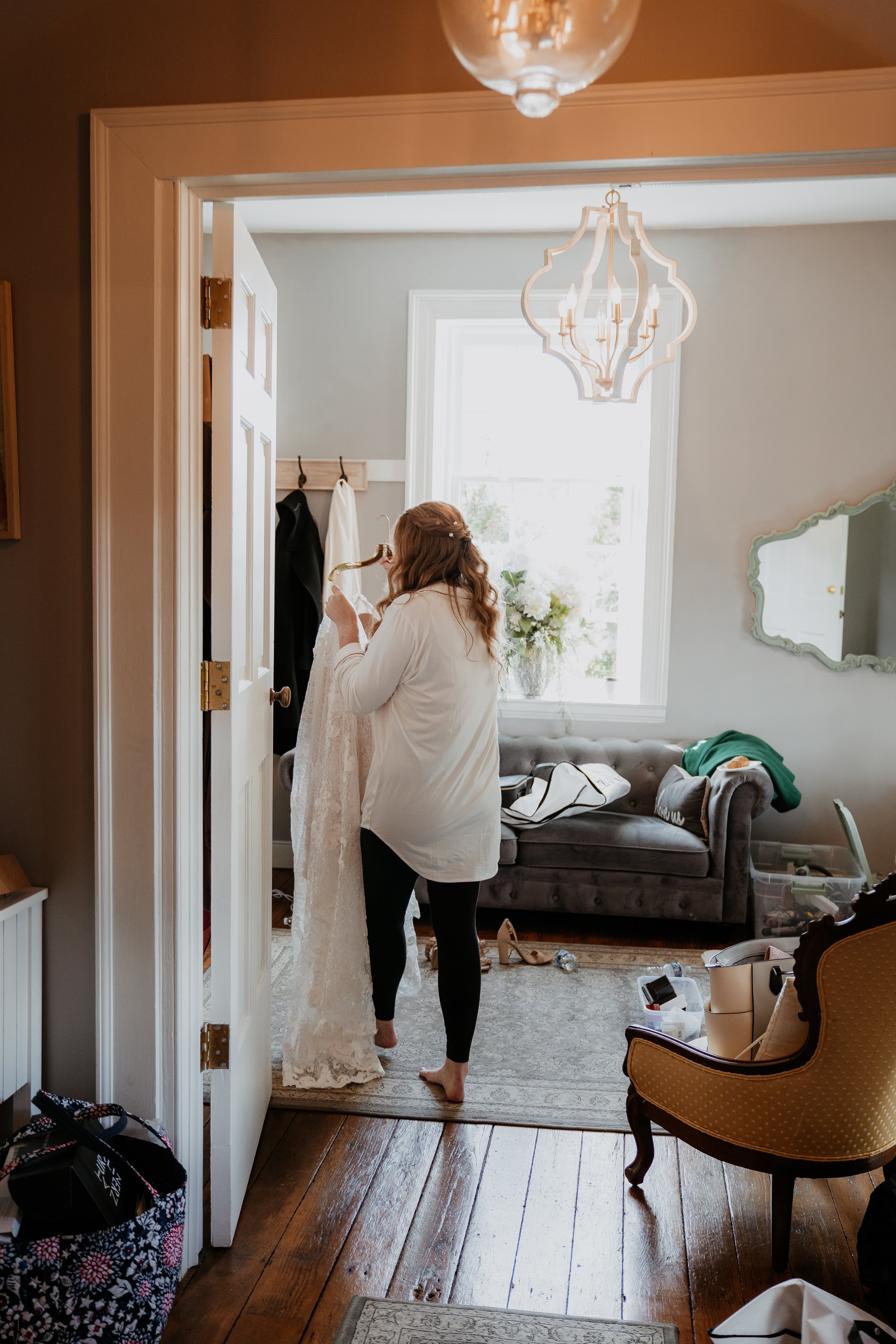 bride carries dress around a corner into a getting ready room at Stone Mill Inn
