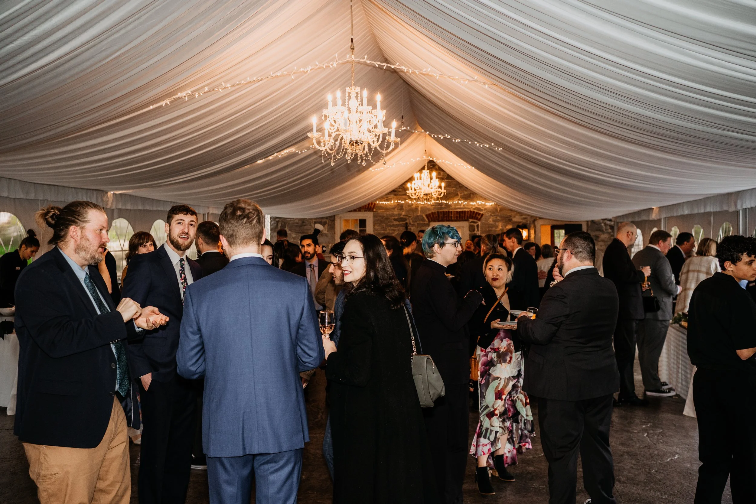 wedding guests mingling inside a reception tent at Stone Mill Inn