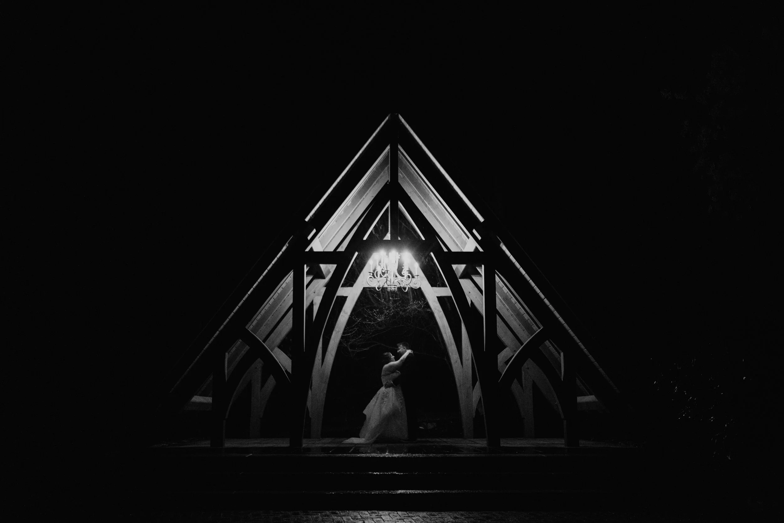 bride and groom embrace under the Abbey ceremony location at Stone Mill Inn