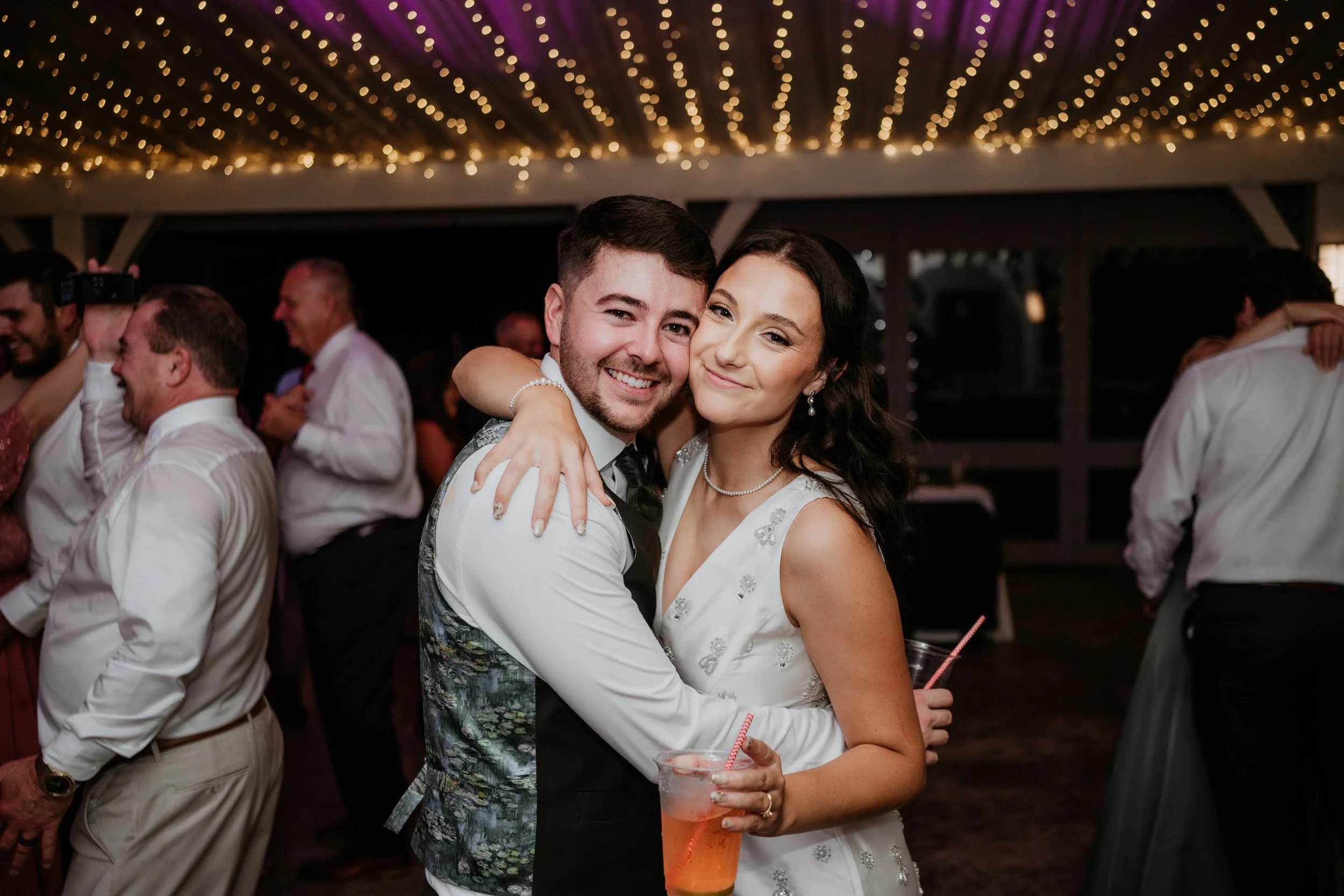 bride and groom embrace while smiling and dancing at their wedding reception in a tent at moonstone manor