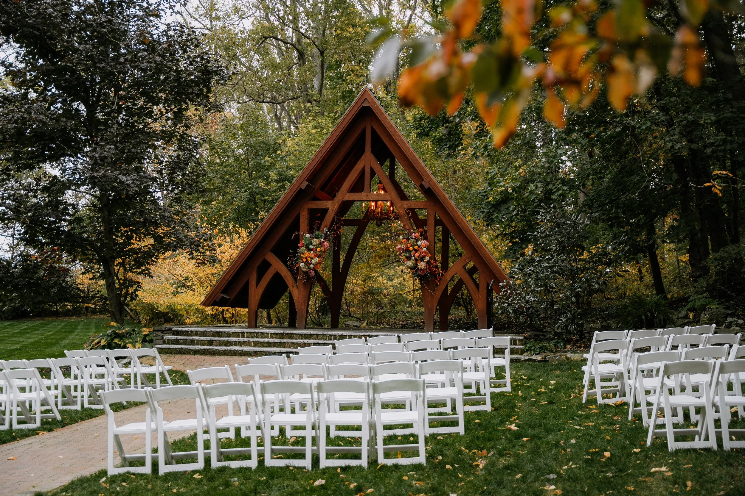 Outdoor wedding ceremony setup with white chairs and wooden arbor at Stone Mill Inn in Hallam, PA