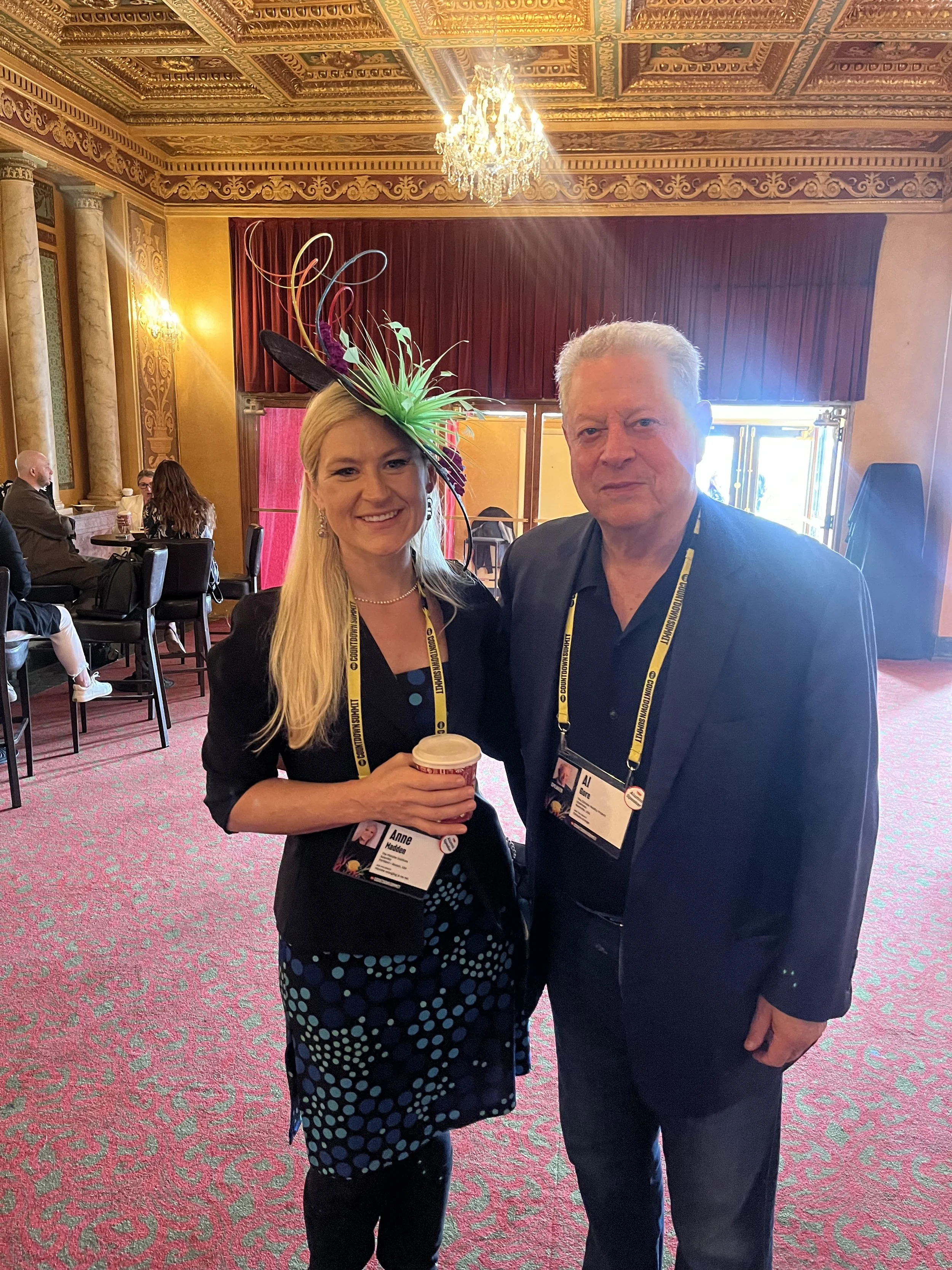Anne A. Madden, (wearing a Microbe Hat featuring a 3D print of the PCR-enabling enzyme that came from an extremophile microbe) (left), next to climate activist and former Vice President of the USA, Al Gore (right).