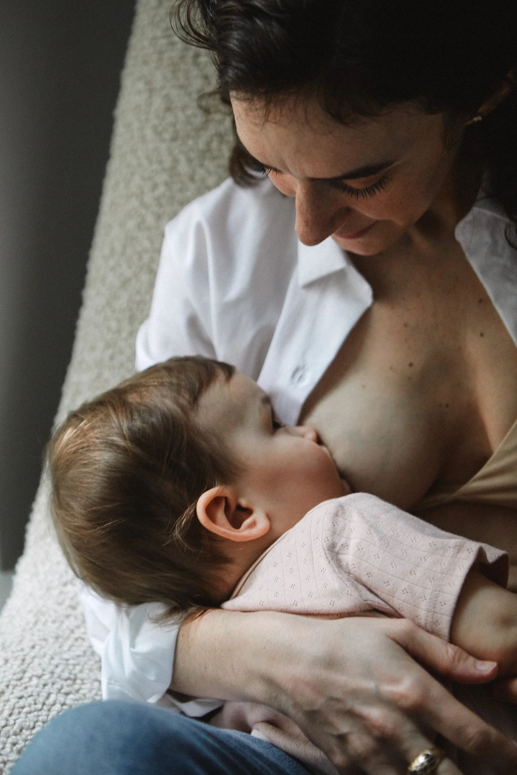 breastfeeding mother child eye gazing snuggling chair natural light