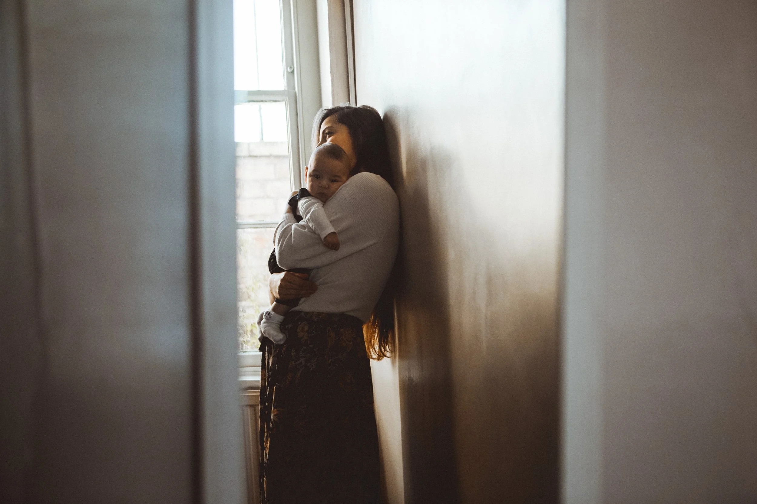mother holding baby by window doorway