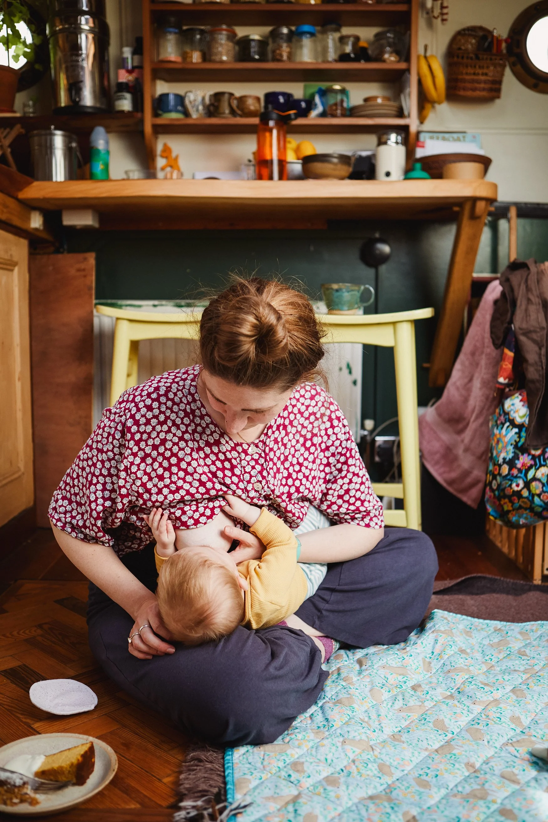 breastfeeding messy kitchen mother baby sitting floor warm tones