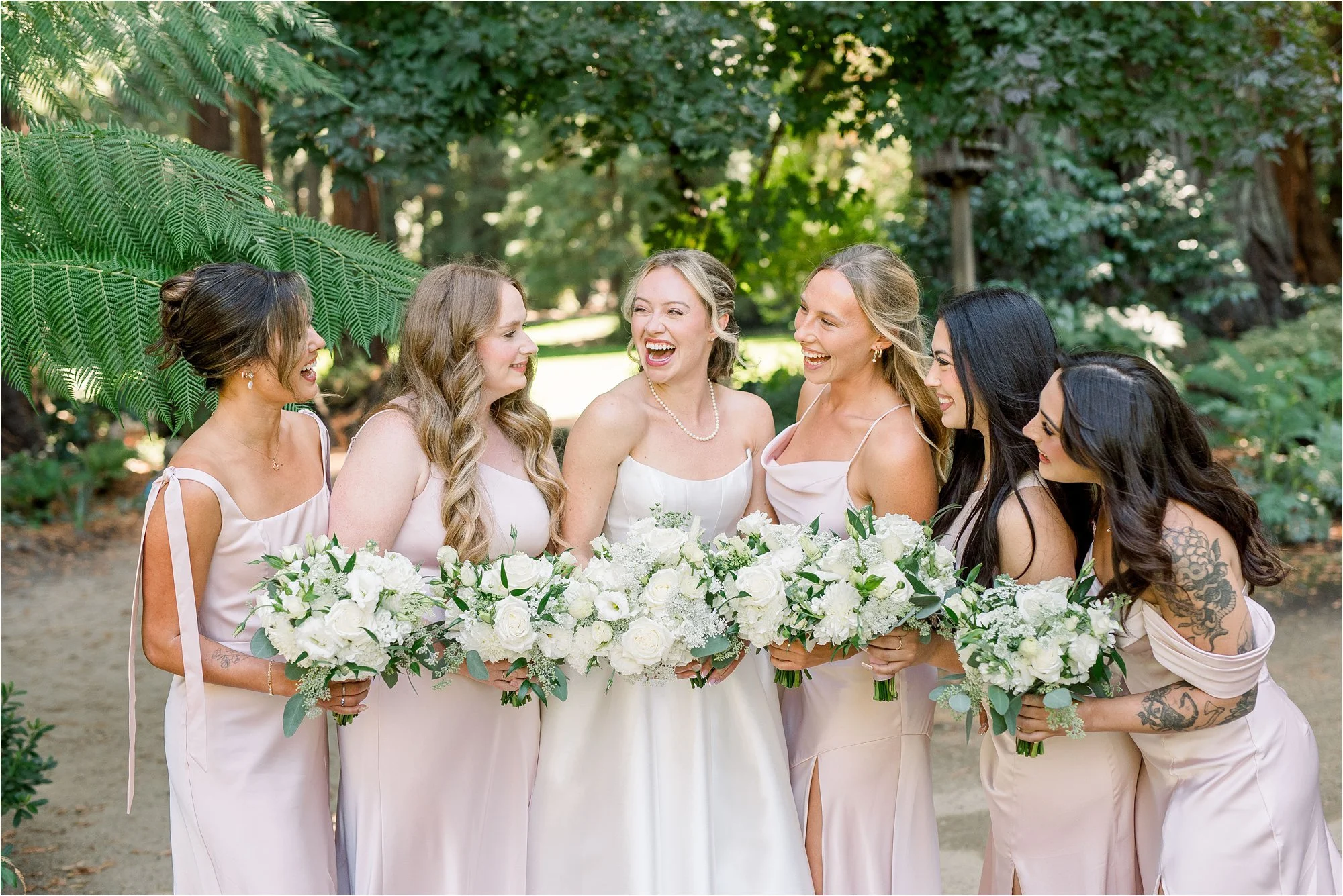 Bridesmaids wearing soft pink satin dresses and laughing together