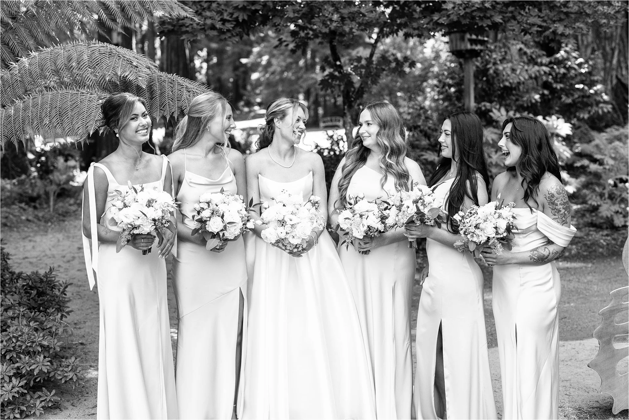 Black and white photo of Alexandra and her bridesmaids smiling and looking at each other