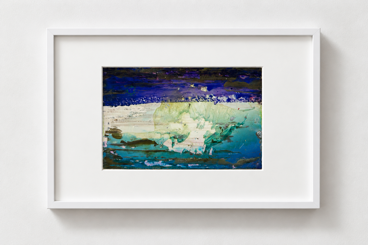 Abstract watercolor painting with shades of blue, green, and purple framed in white hanging on a white wall.