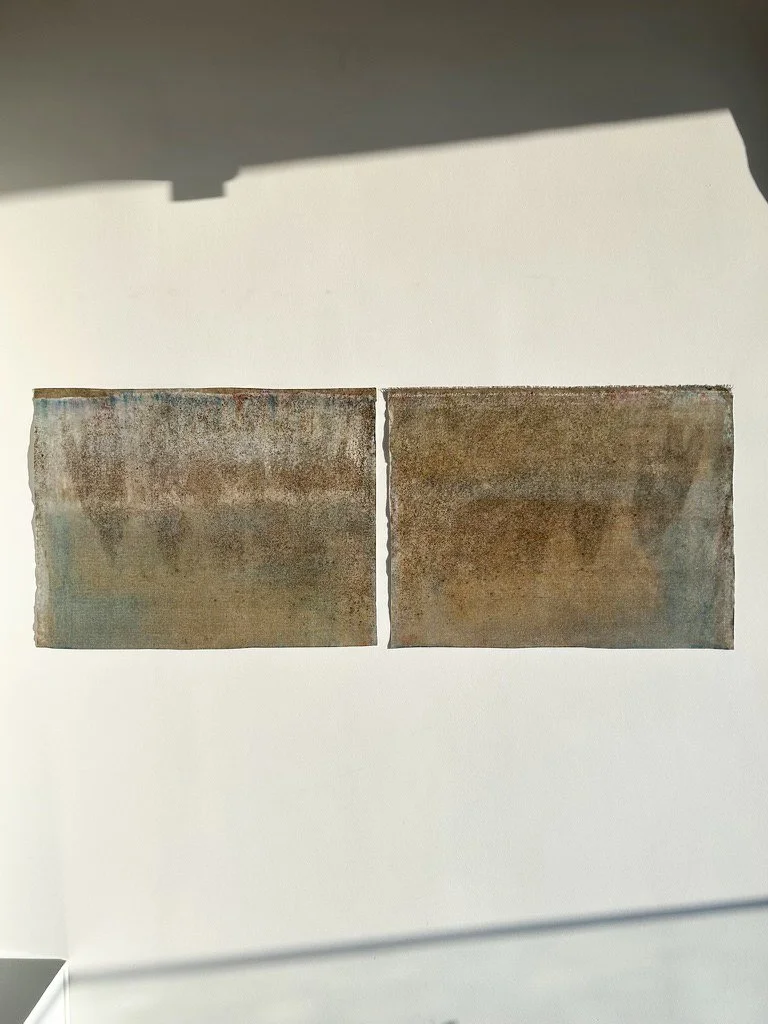 Two rusted metal sheets mounted on a white wall.